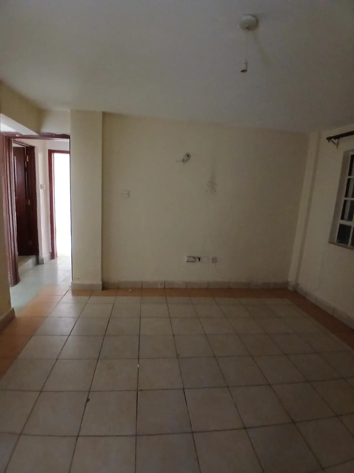 Spacious empty living area with tiled flooring and natural light