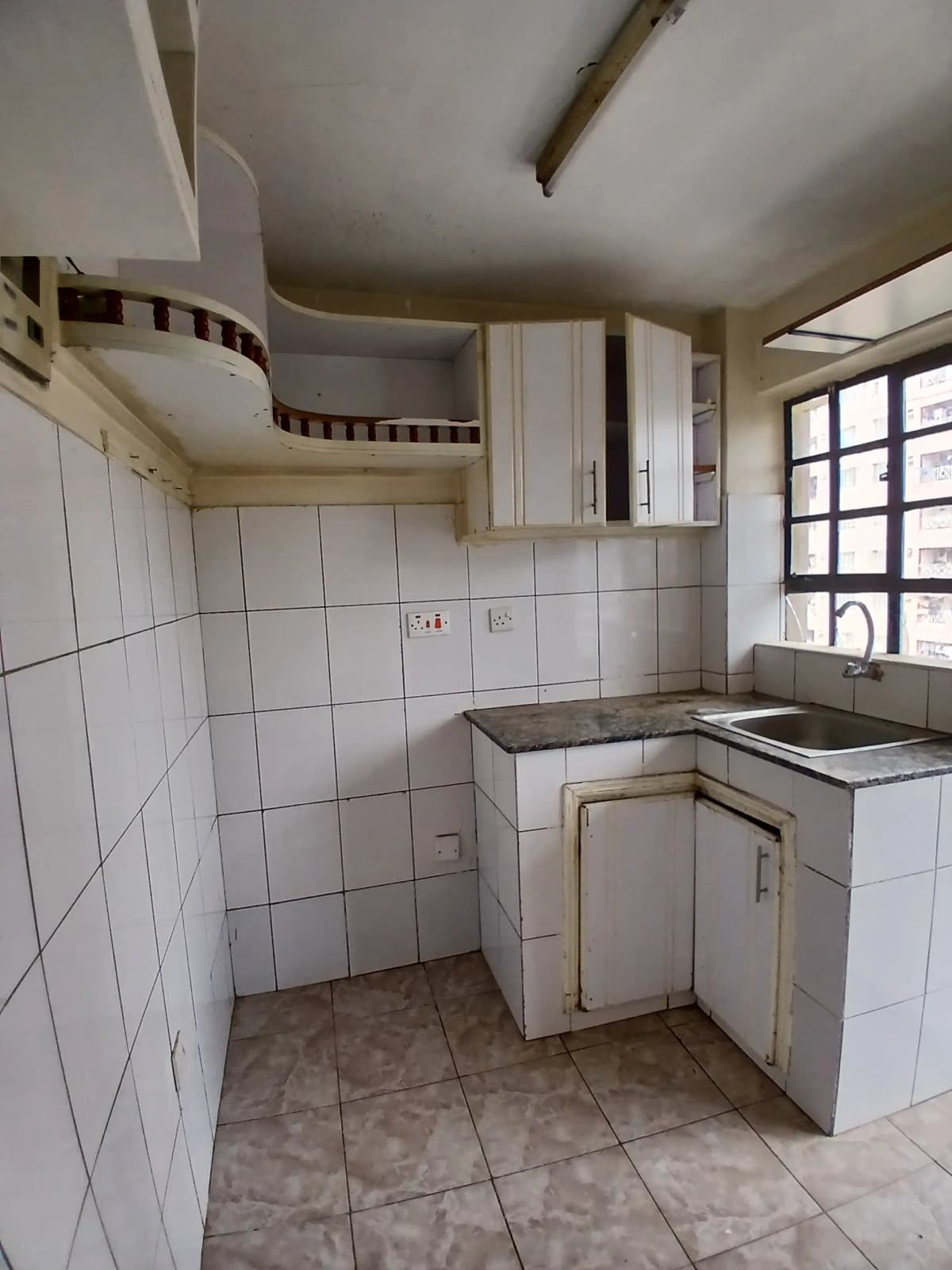 Compact kitchen with white tile backsplash and basic cabinetry