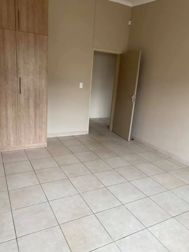 Spacious bedroom with tiled flooring and built-in wardrobes