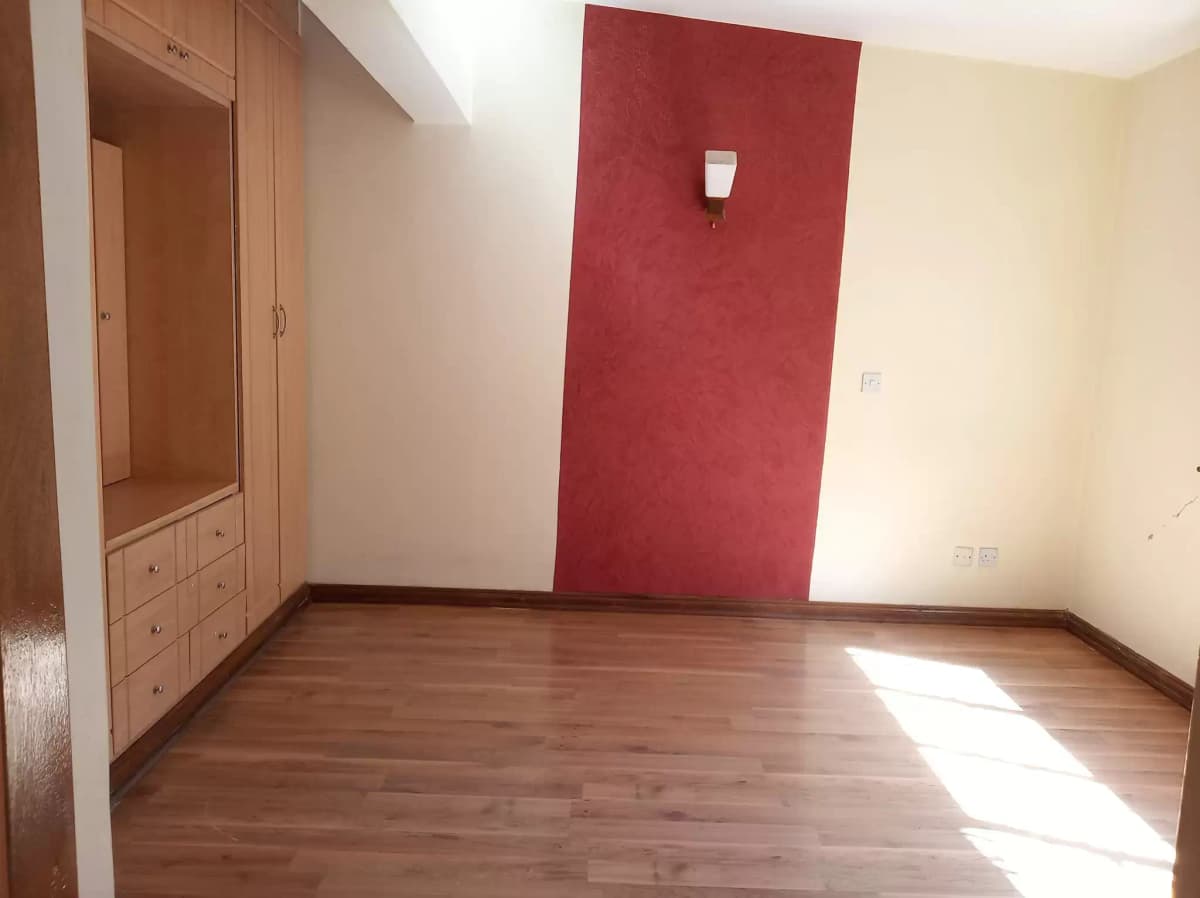 Spacious bedroom with wooden flooring and accent wall