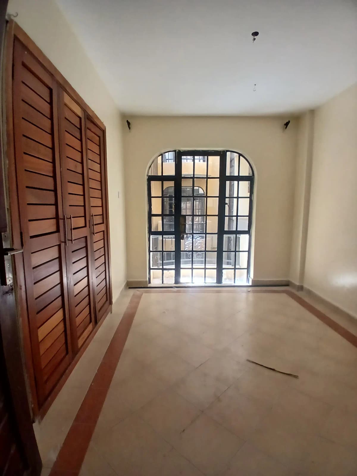 Empty living room with wooden louvered doors and barred entrance