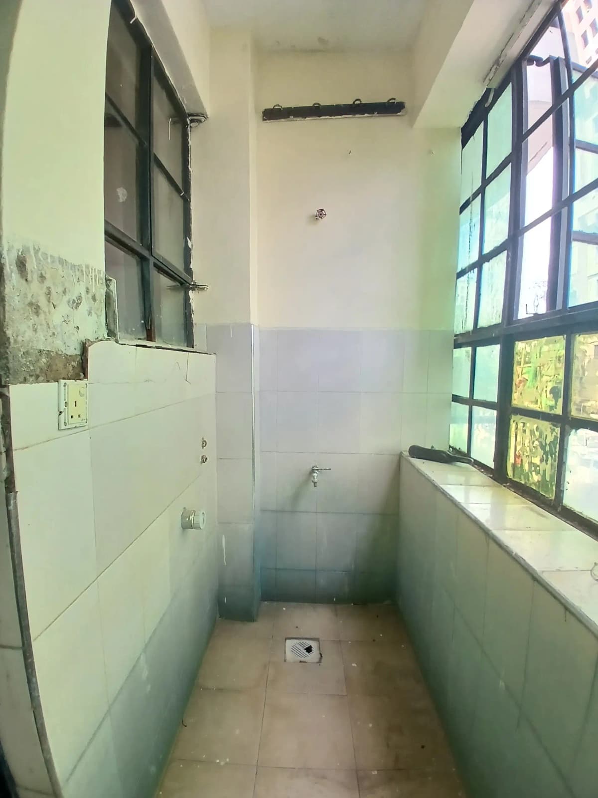 Narrow utility room with tiled walls and barred windows