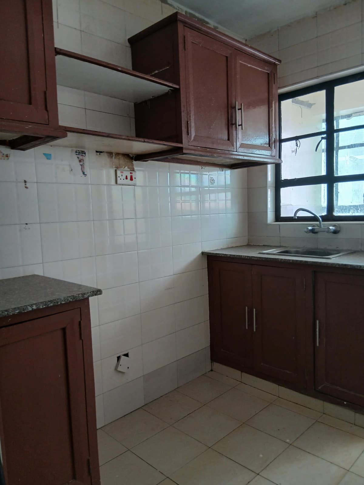 Compact kitchen with dark cabinetry, white tile backsplash, window