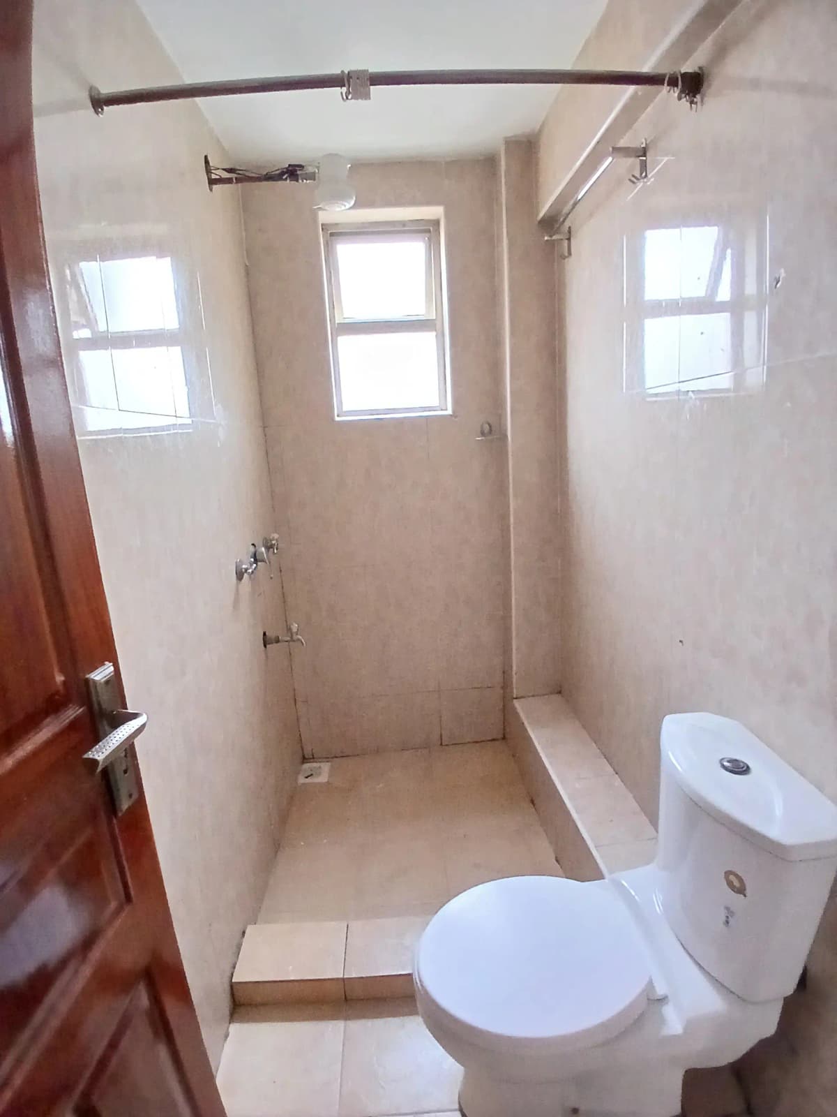 Compact bathroom with toilet, shower area, and natural light