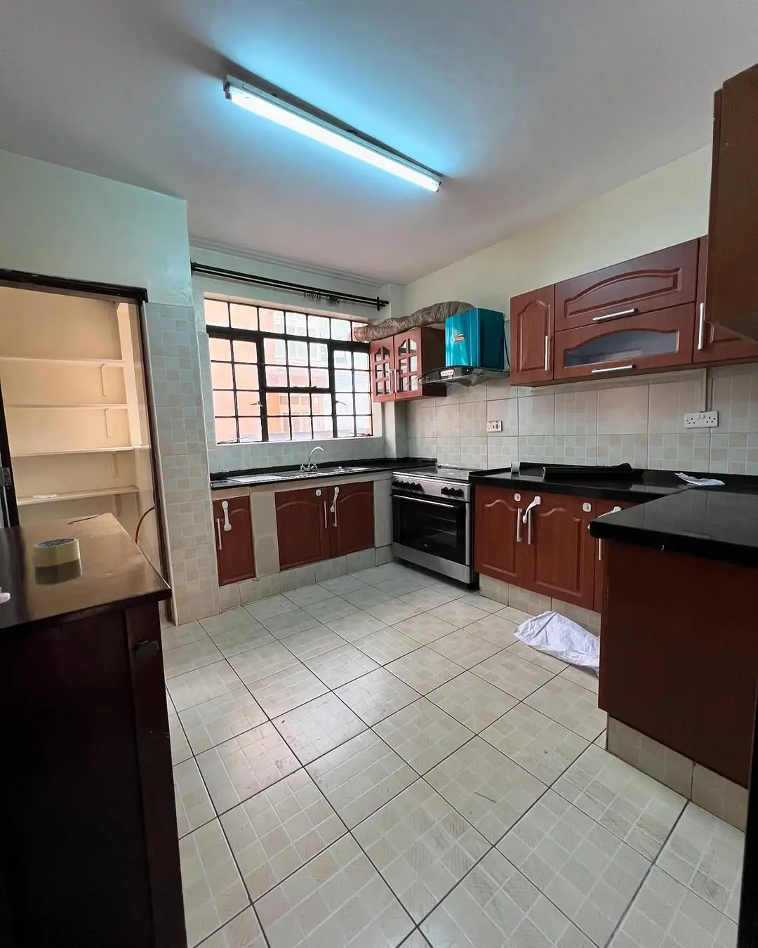 Modern kitchen with wooden cabinets, black countertops, tiled floor