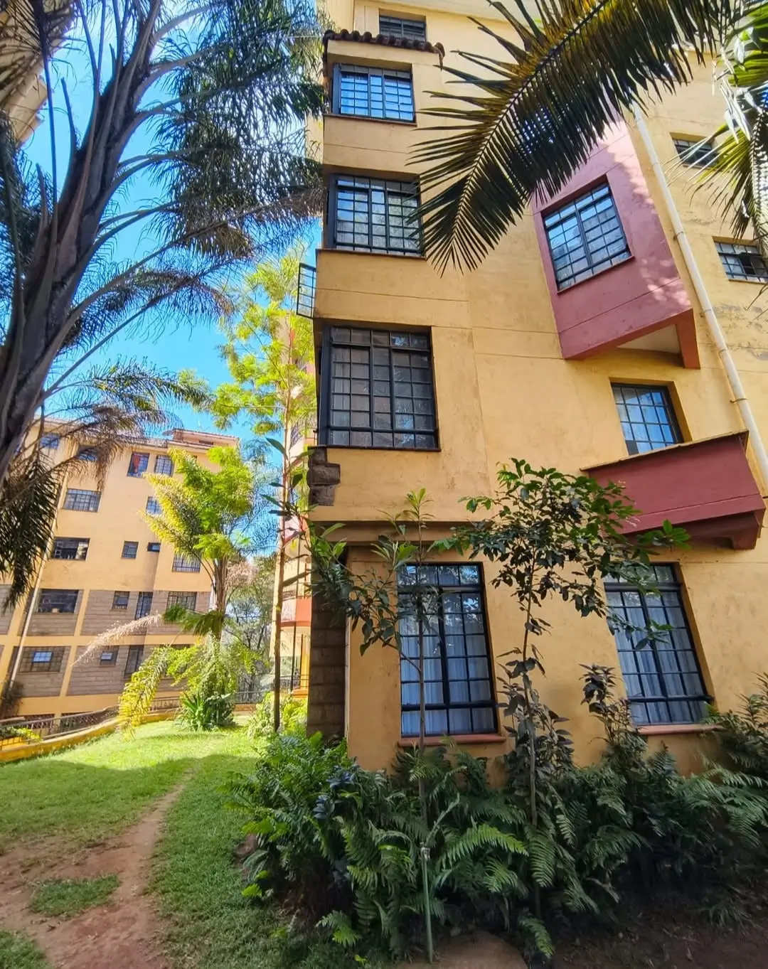 Yellow-ochre residential building facade with manicured grounds