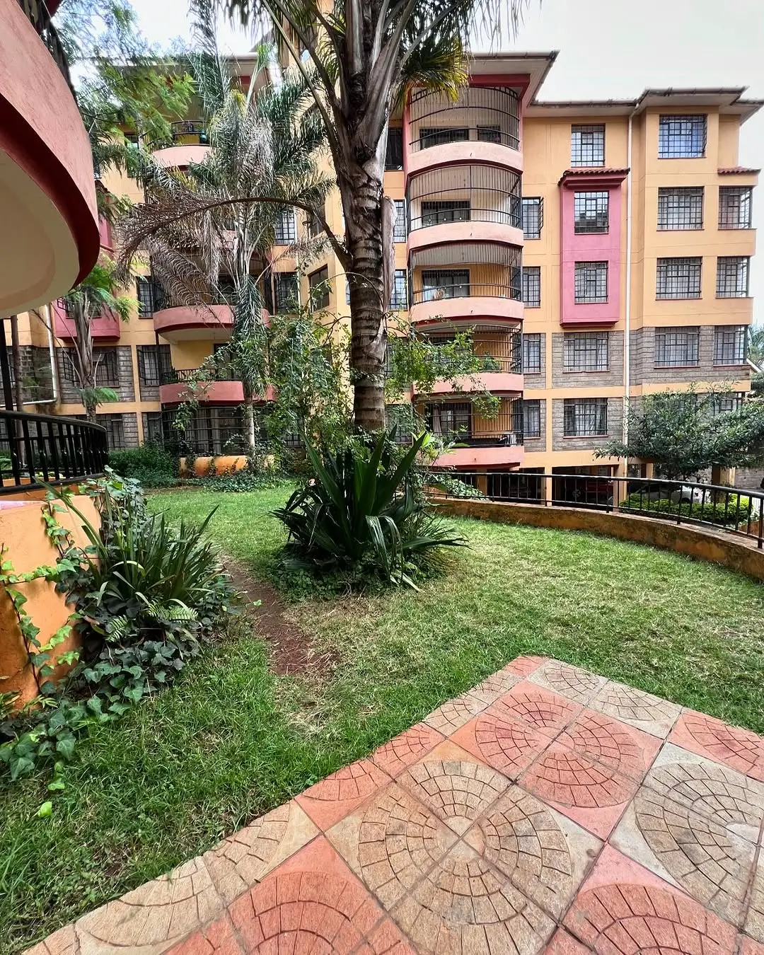 Landscaped compound garden with lawn, mature palms, paved pathways