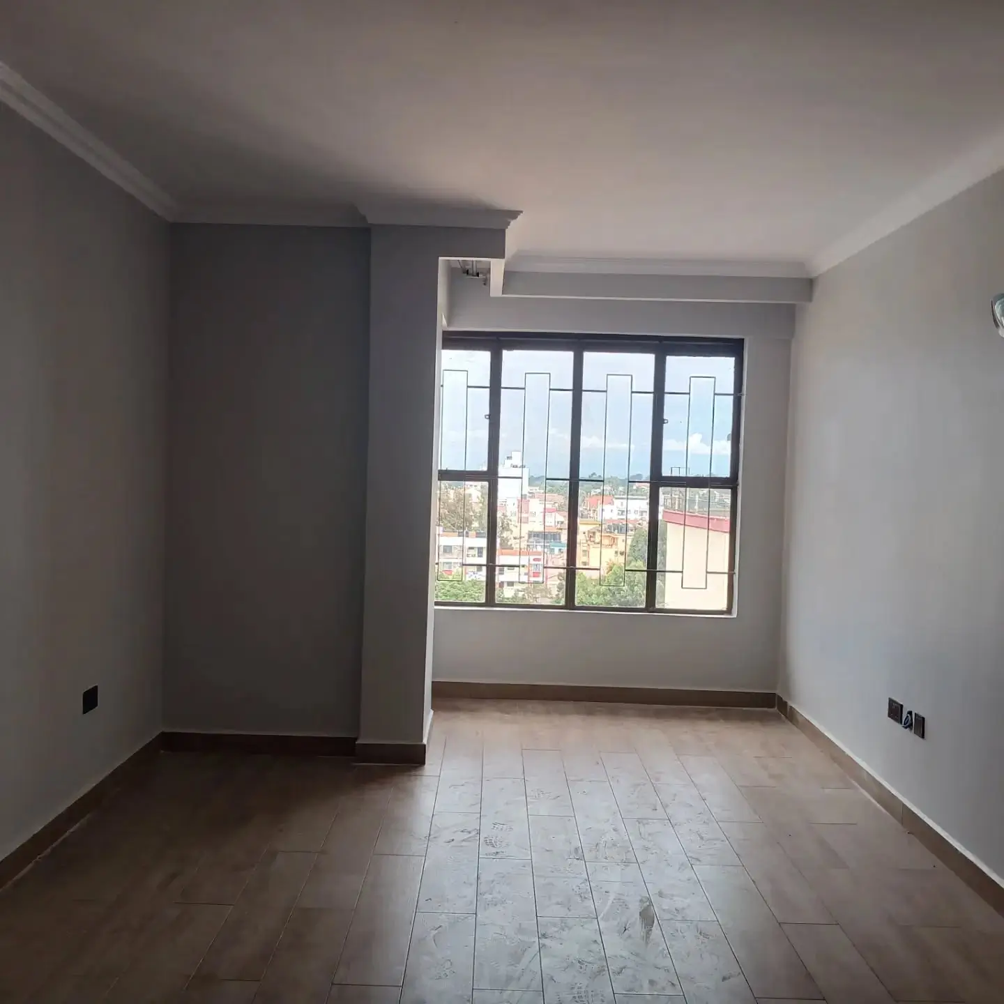 Spacious bedroom with large windows overlooking residential area