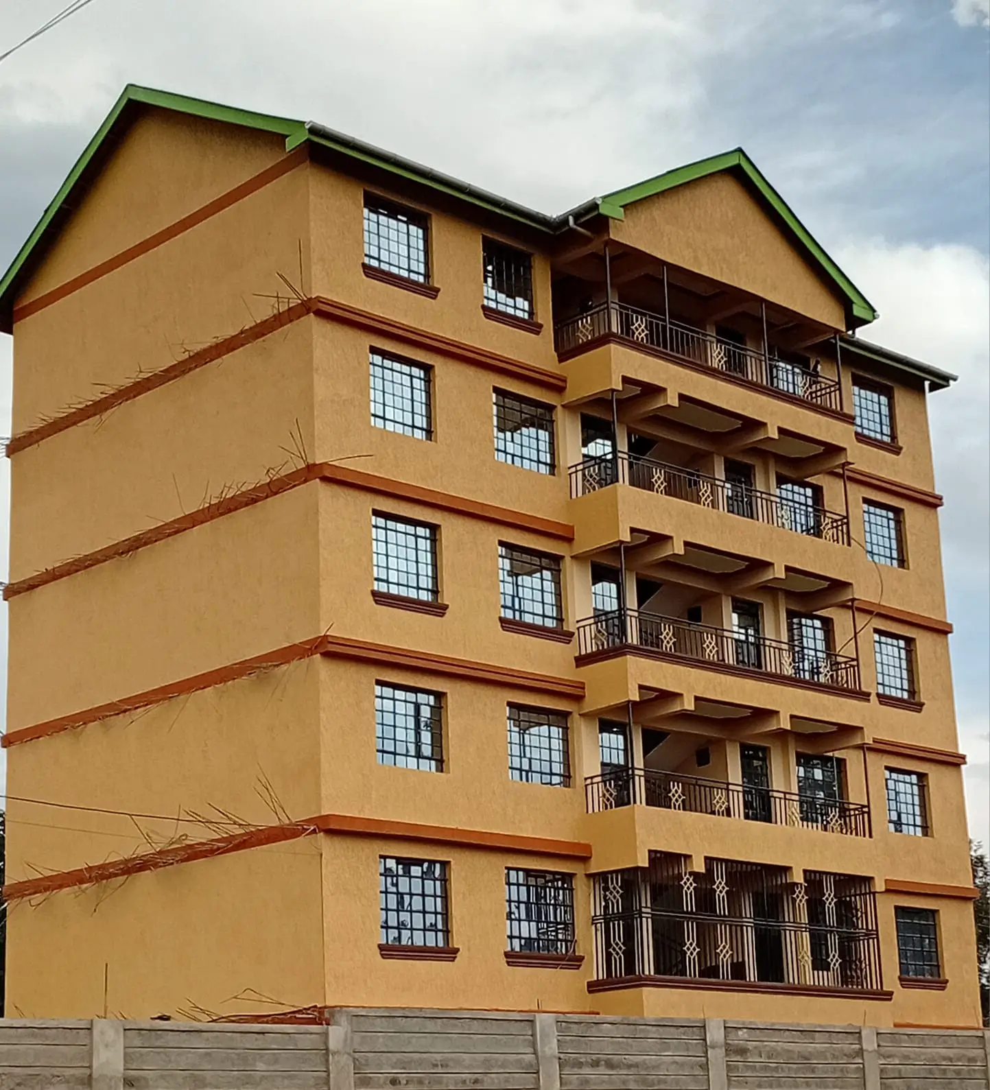 Five-story residential building with yellow facade and balconies
