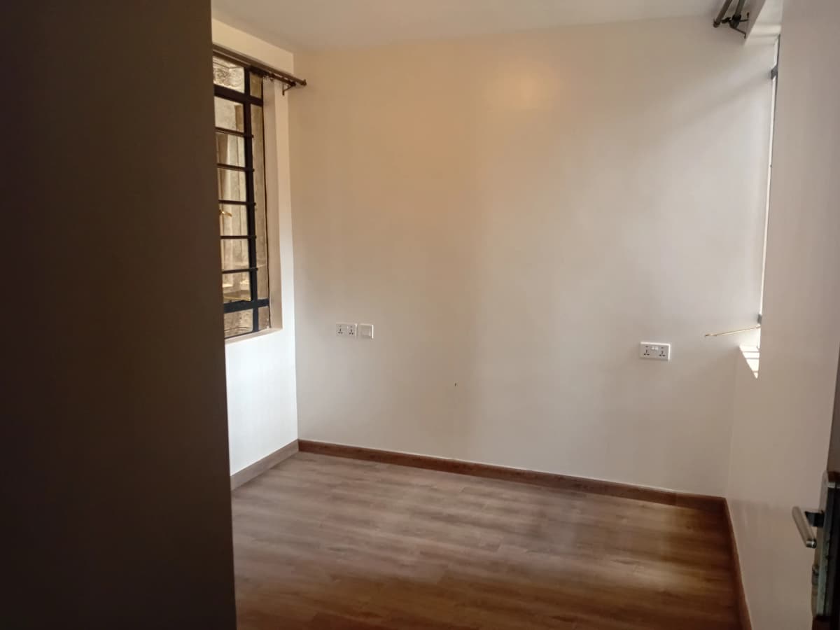 Empty bedroom with wooden flooring and natural light
