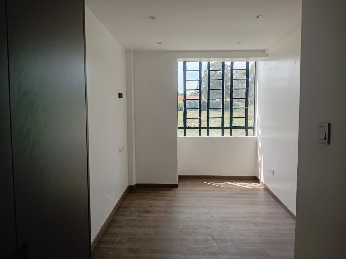 Bright unfurnished bedroom with large window and wooden flooring