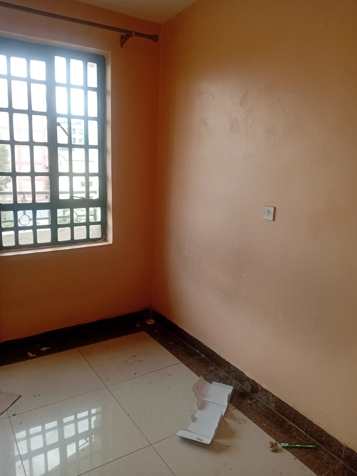 Empty bedroom with window, orange walls, tiled floor