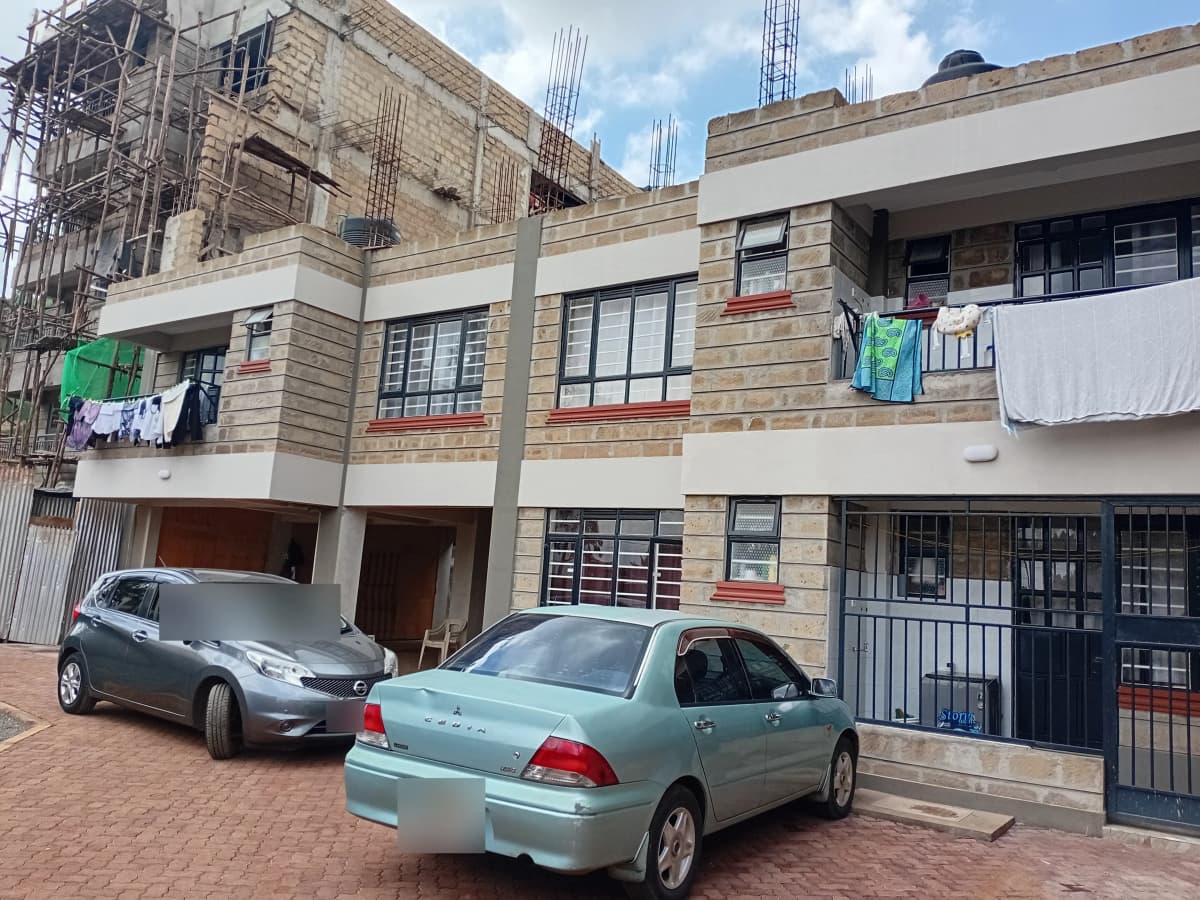 Multi-story residential building with brick facade and parked vehicles