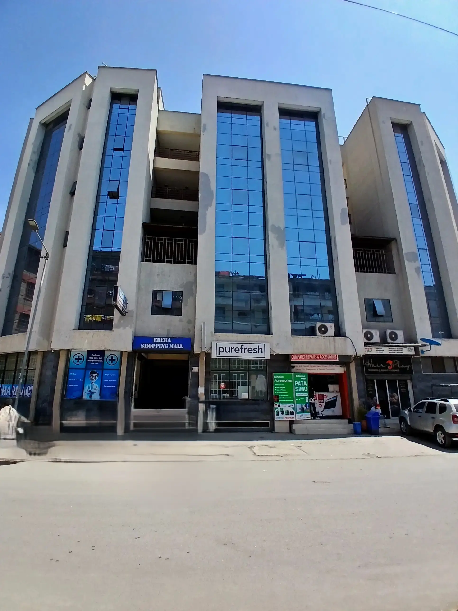 Modern multi-story residential building with glass facade and ground-floor shops