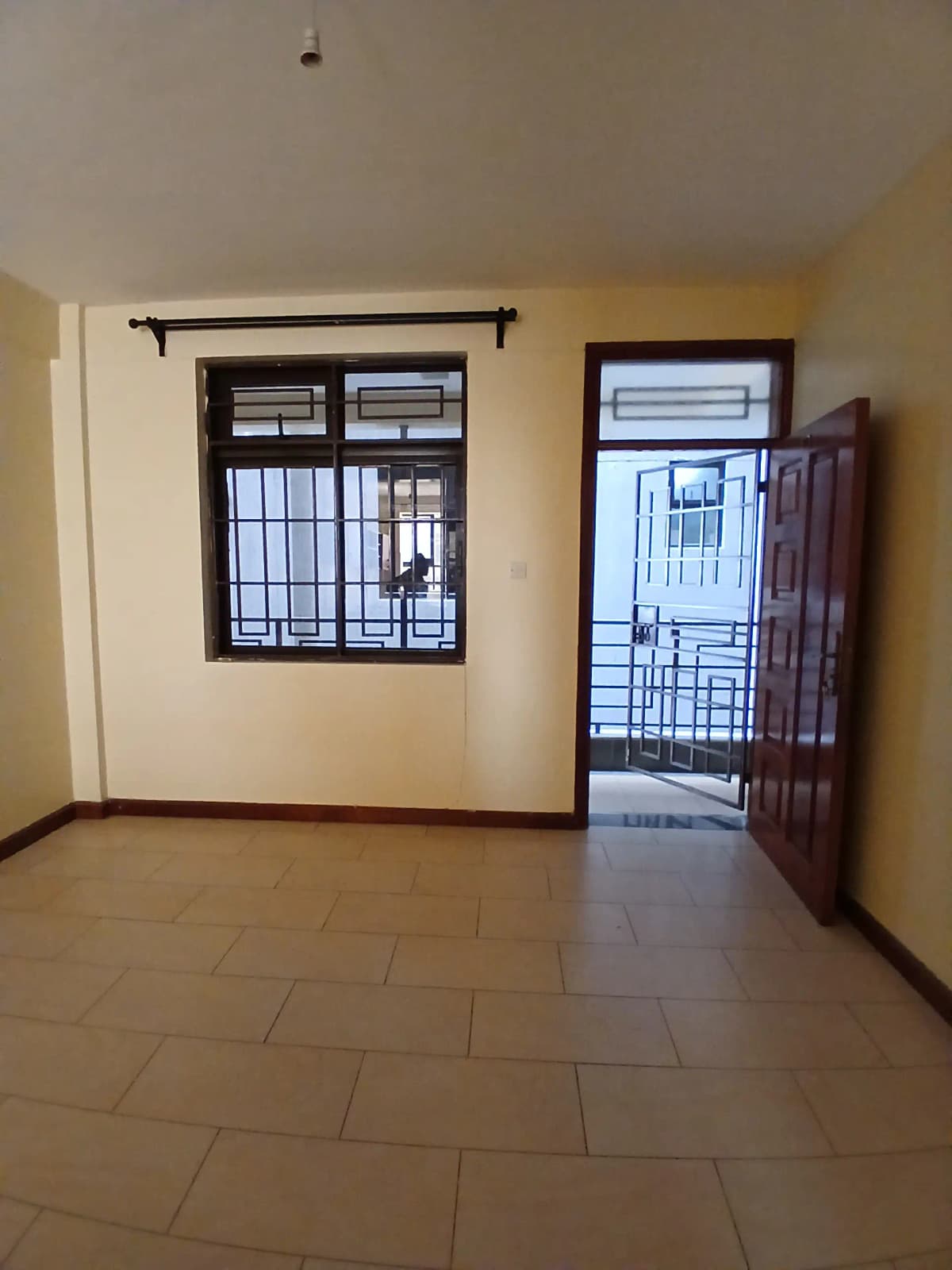 Empty living room with barred windows and terracotta tile flooring
