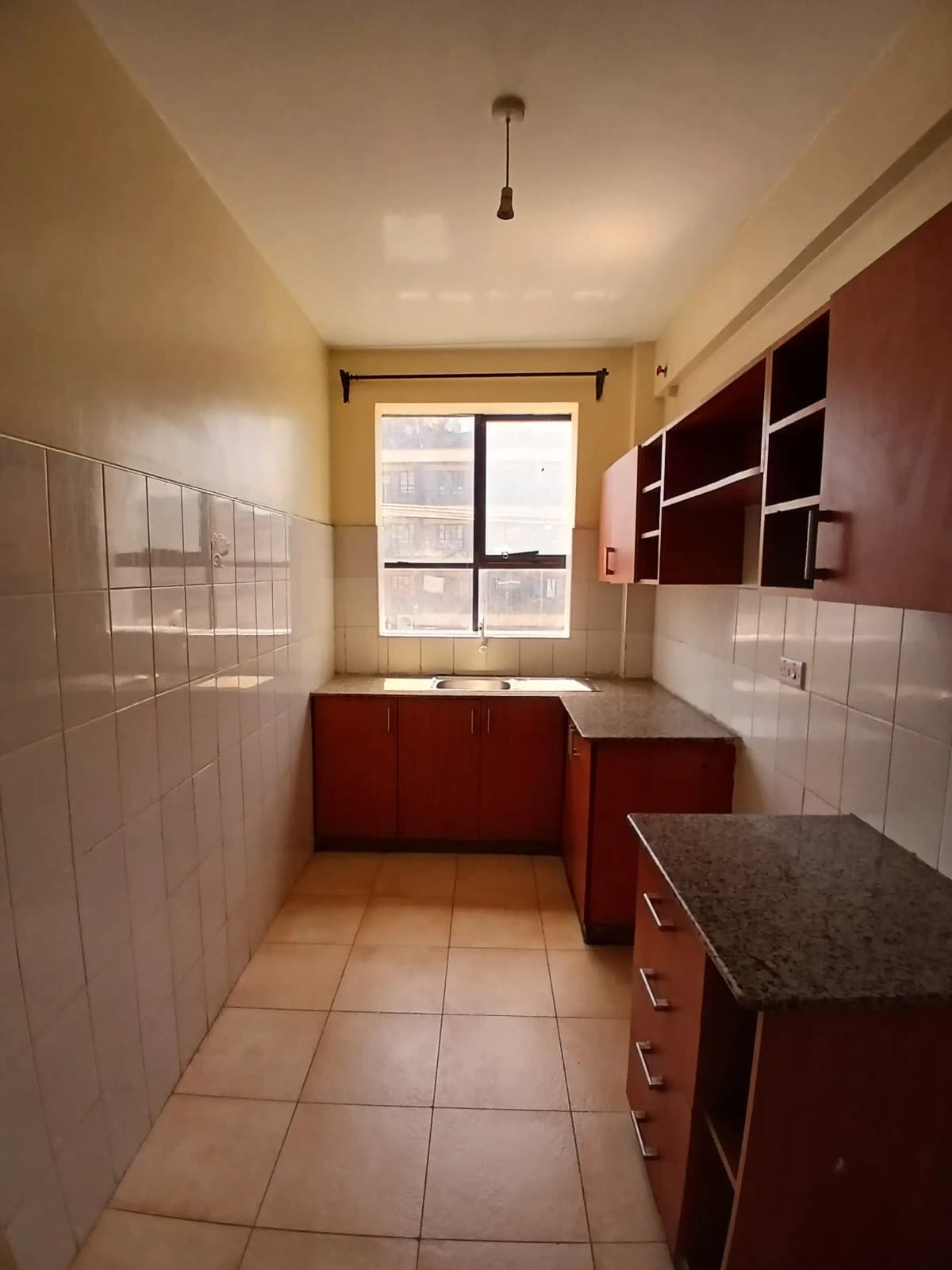 Galley kitchen with burgundy cabinetry and tiled countertops