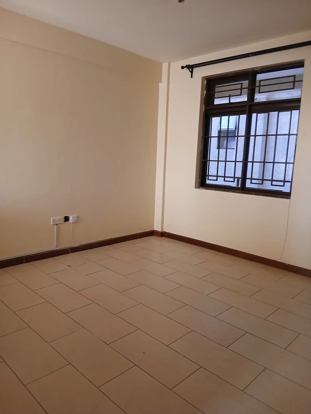 Empty bedroom with tiled floor and barred window