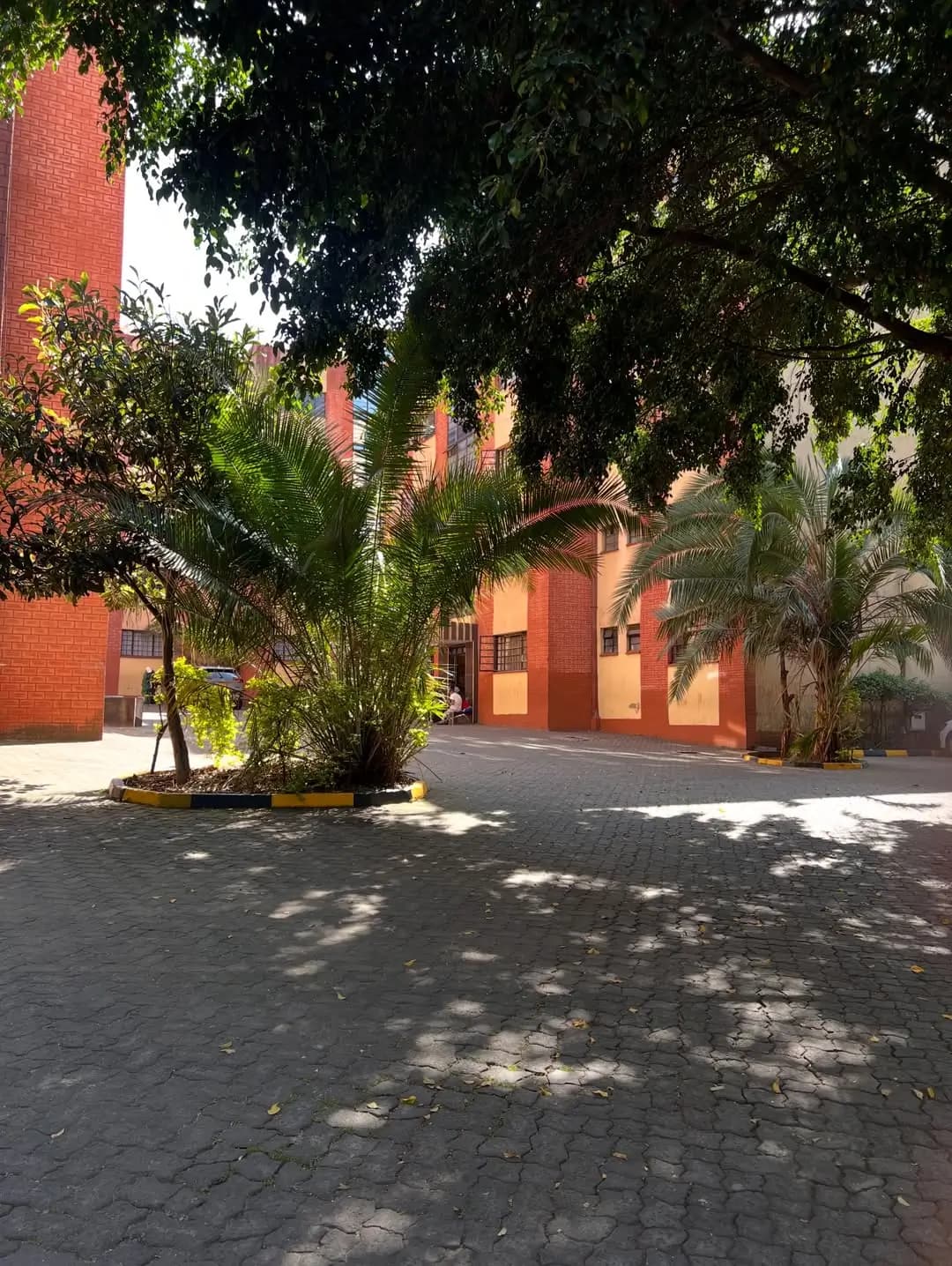 Red brick building facade with manicured compound and palm trees