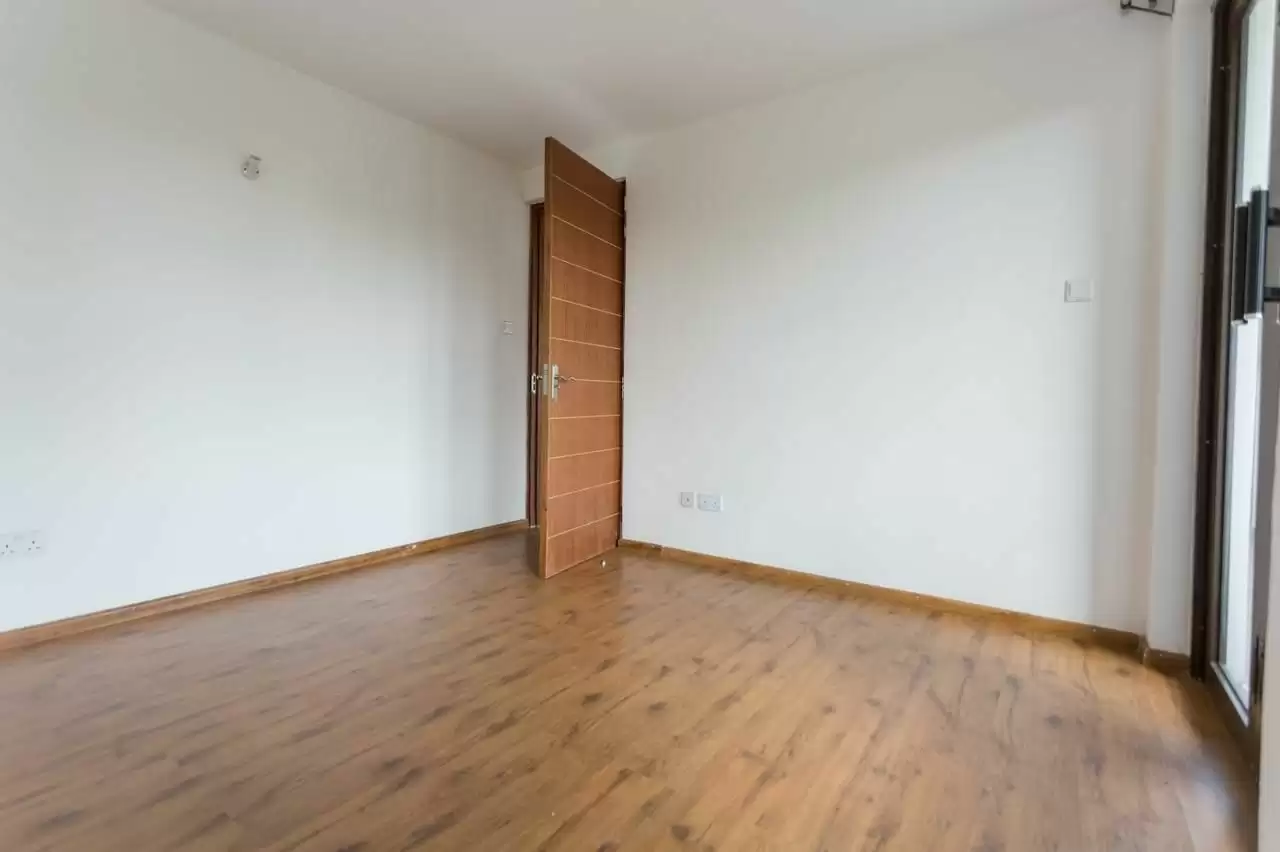 Empty bedroom with wooden door and laminate flooring