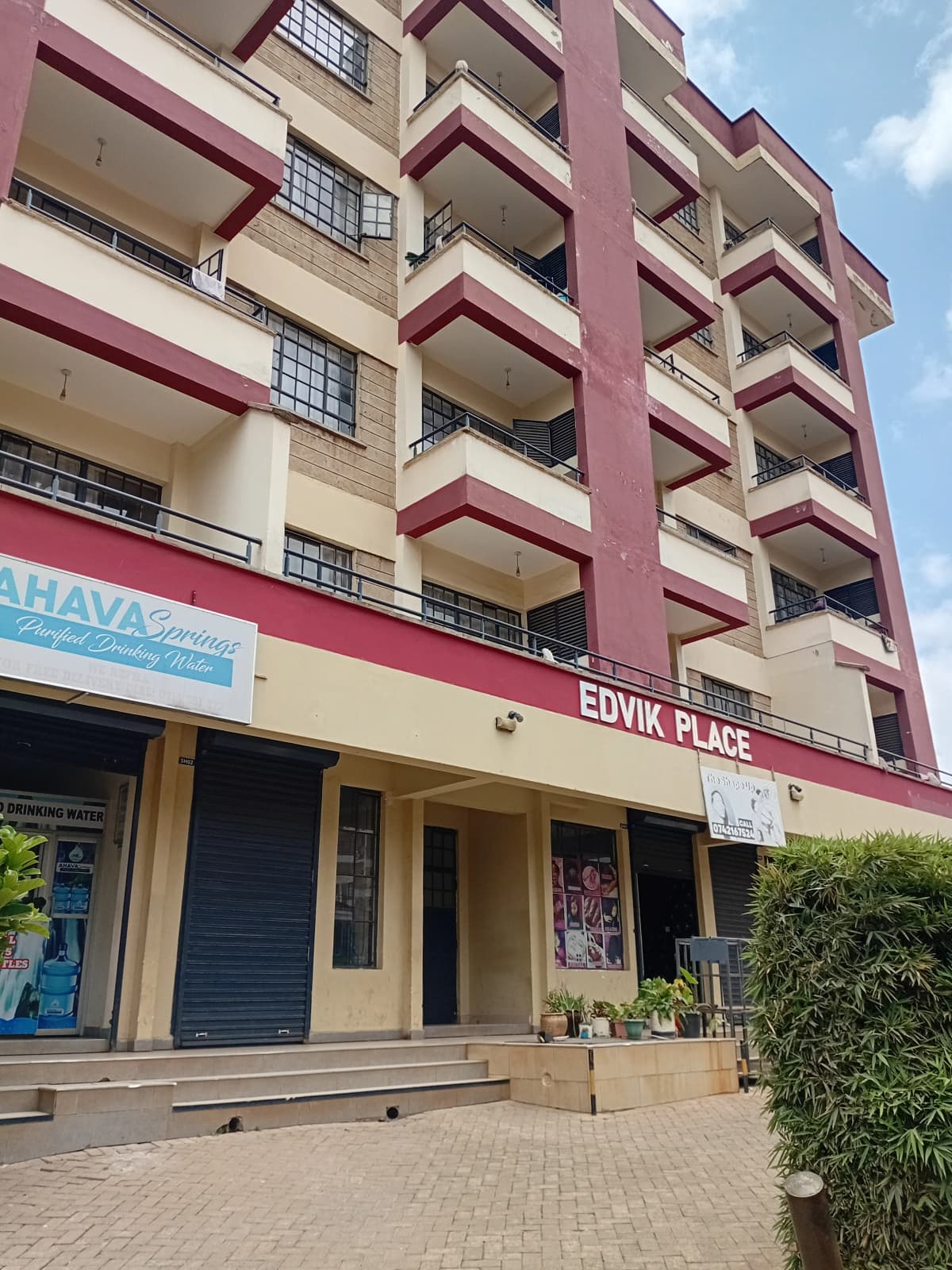 Multi-story residential building with pink and cream facade, ground floor shops