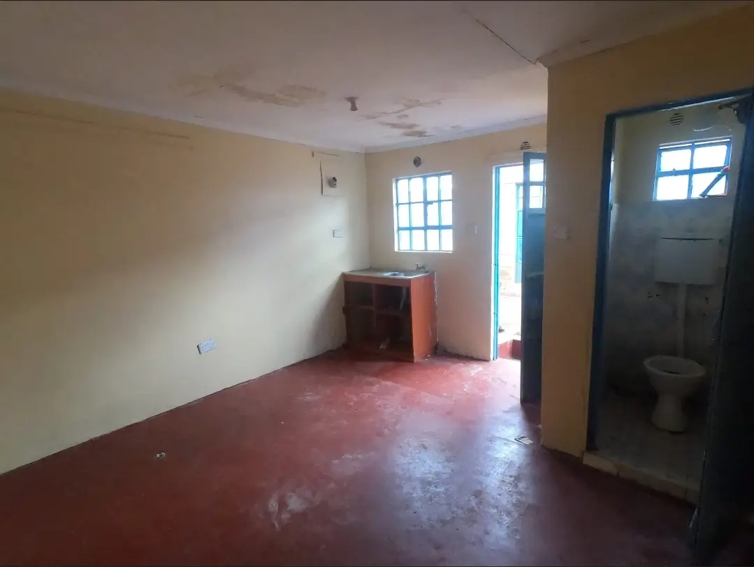 Empty living room with red concrete floor and windows