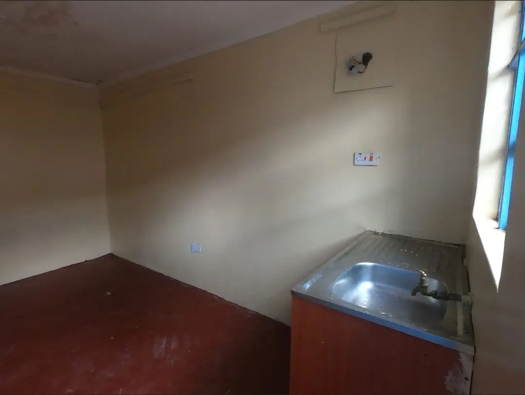 Bare kitchen with sink counter, red flooring, minimal fixtures