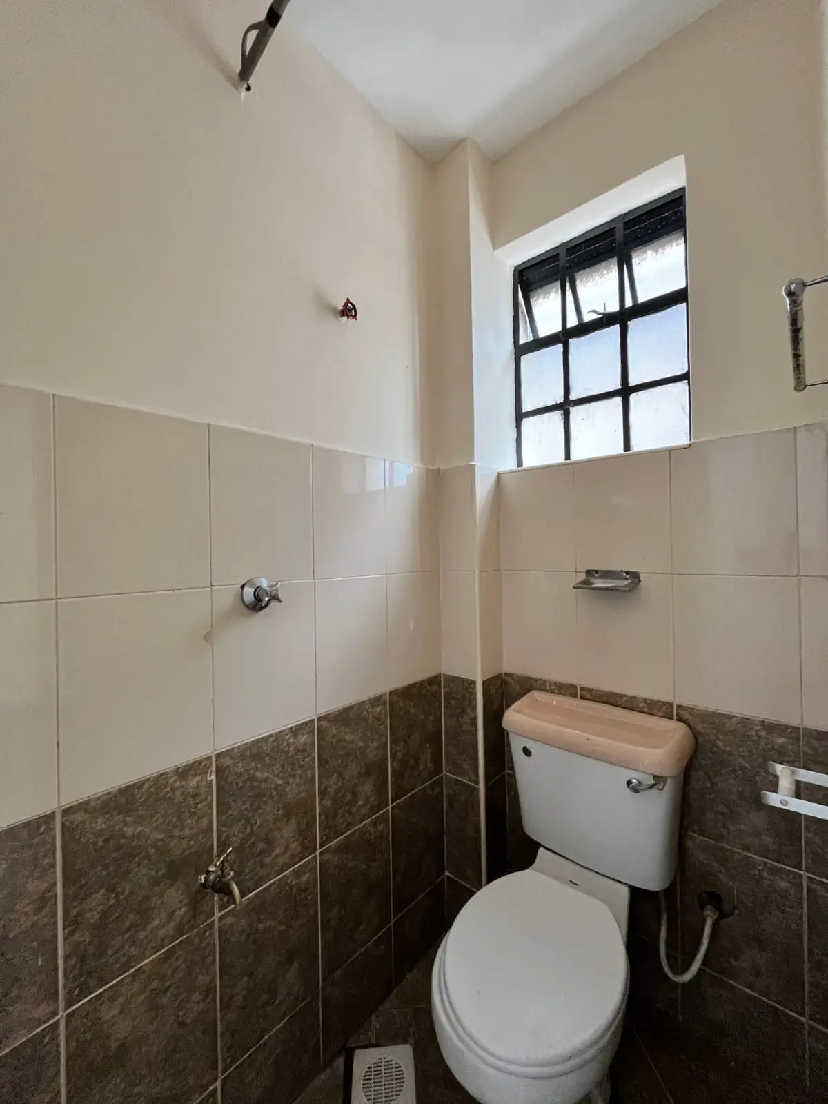 Compact bathroom with toilet, two-tone tile walls, high window