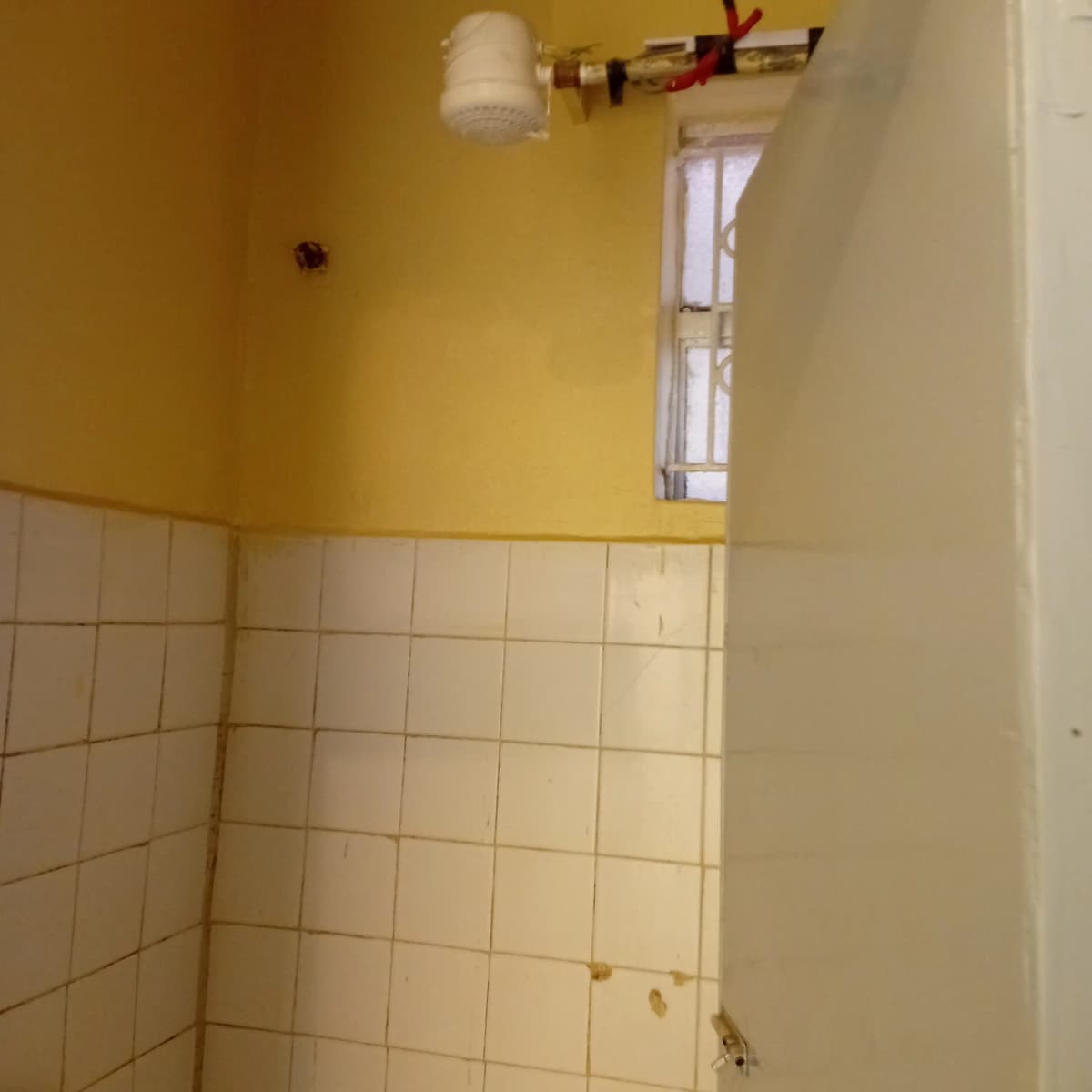 Compact bathroom with white tile walls and yellow upper walls