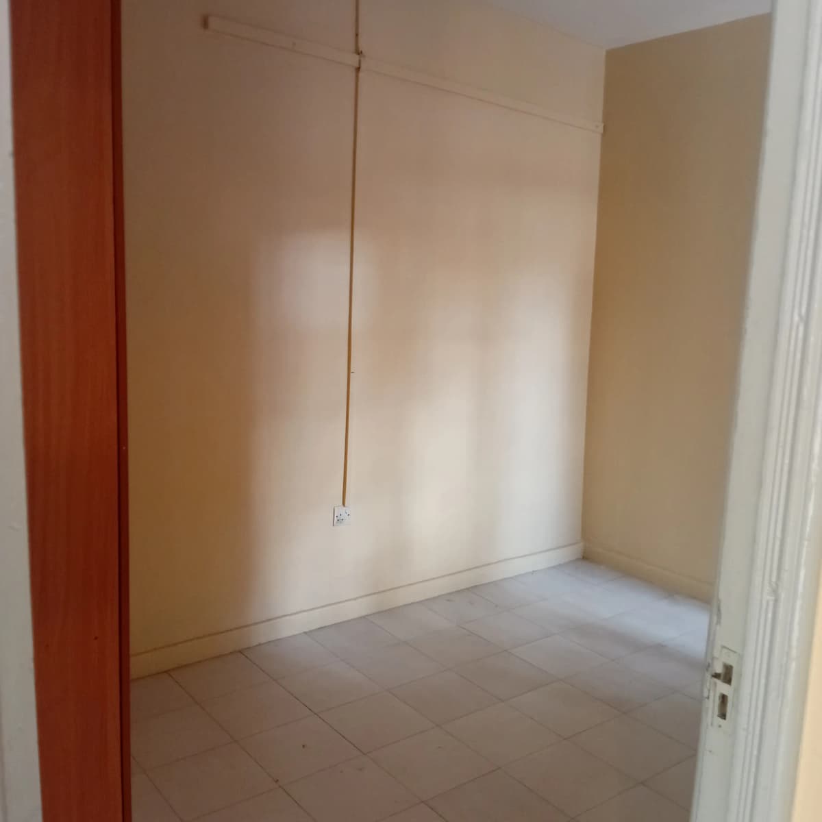 Empty bedroom with tiled floor and built-in wardrobe