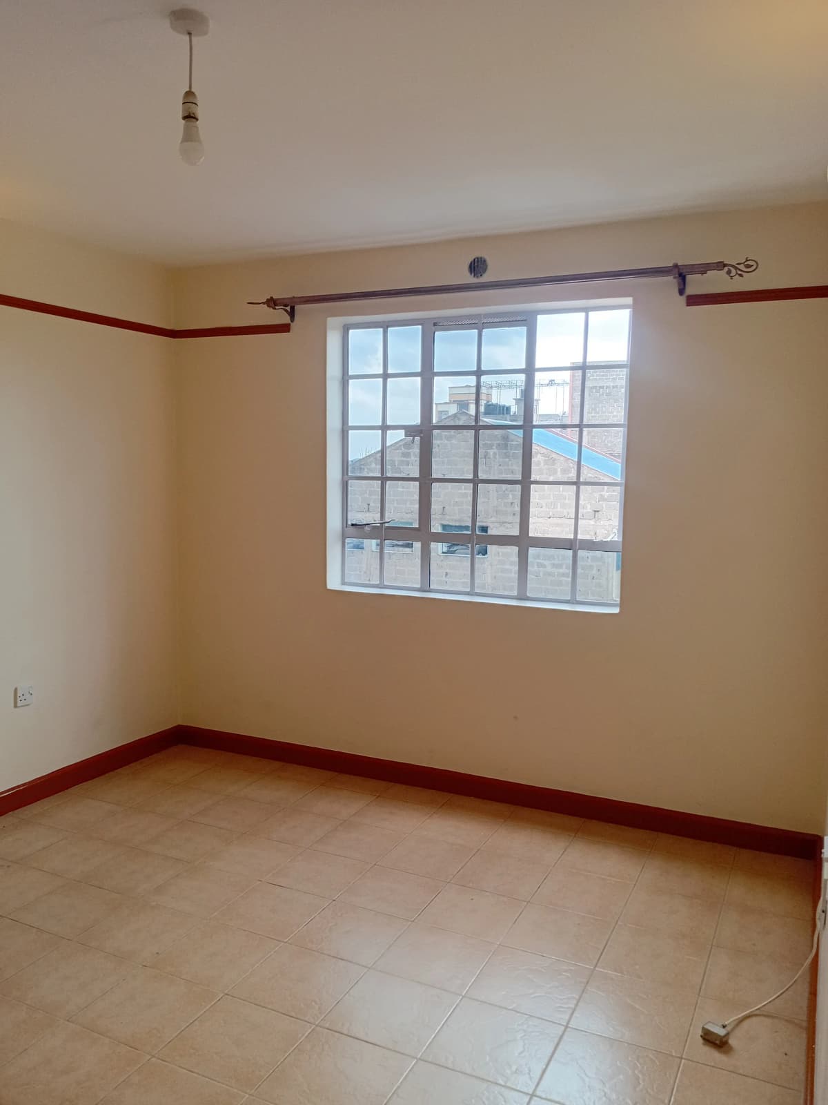 Empty bedroom with large window and terracotta trim