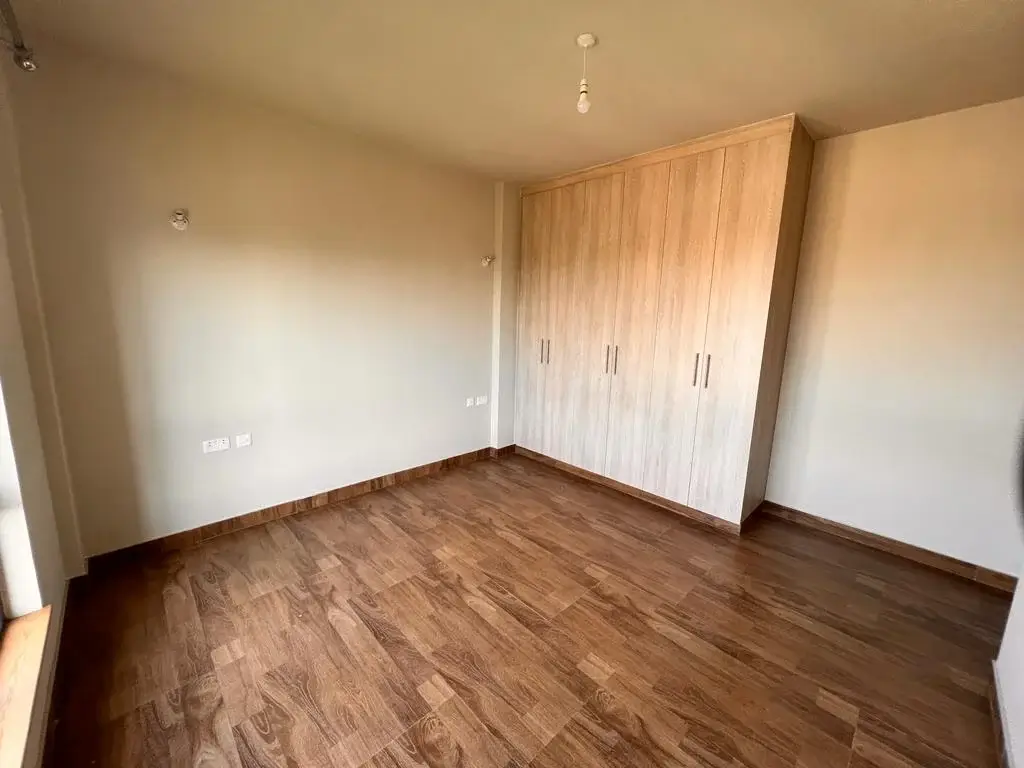 Spacious bedroom with wooden flooring and built-in wardrobes