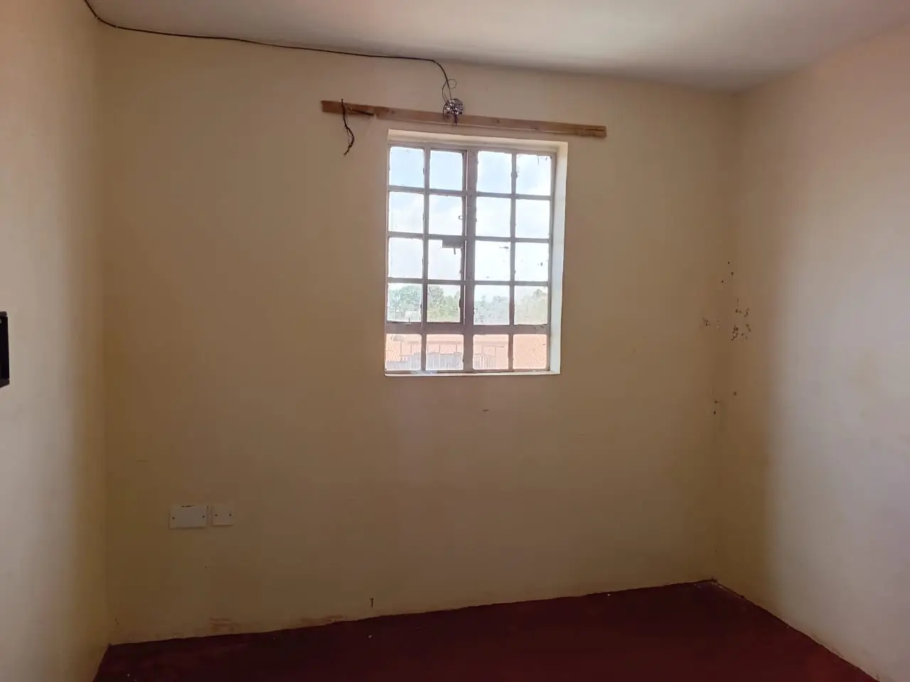 Unfurnished bedroom with large window and minimal fixtures