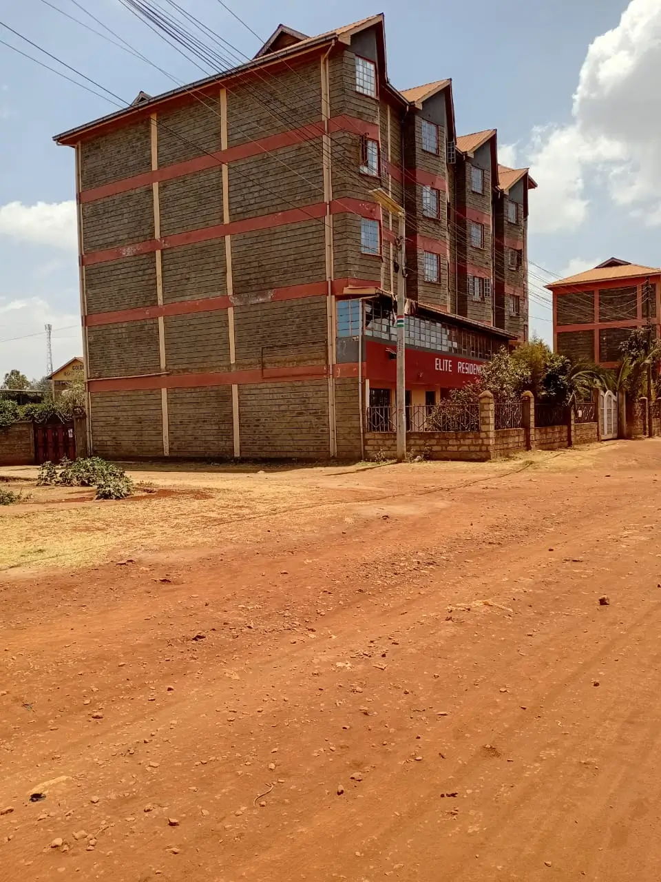 Multi-story brick building with red trim and compound grounds