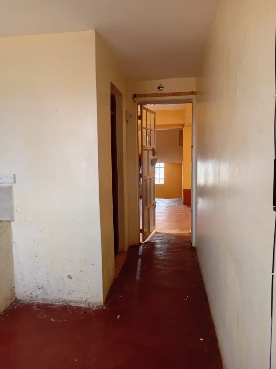 Interior hallway with red concrete floor and wooden doors