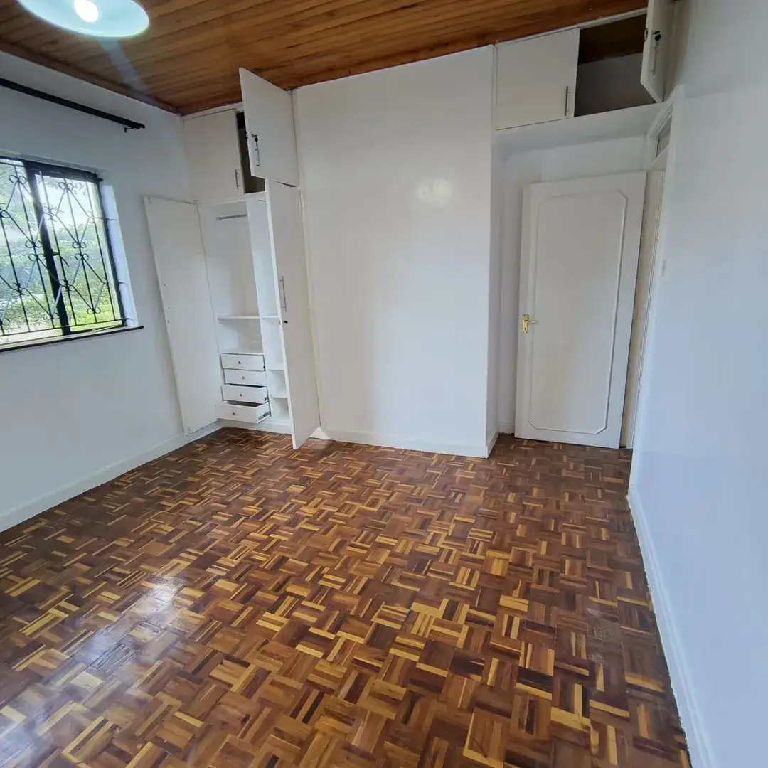 Spacious bedroom with wooden parquet floor and built-in wardrobes