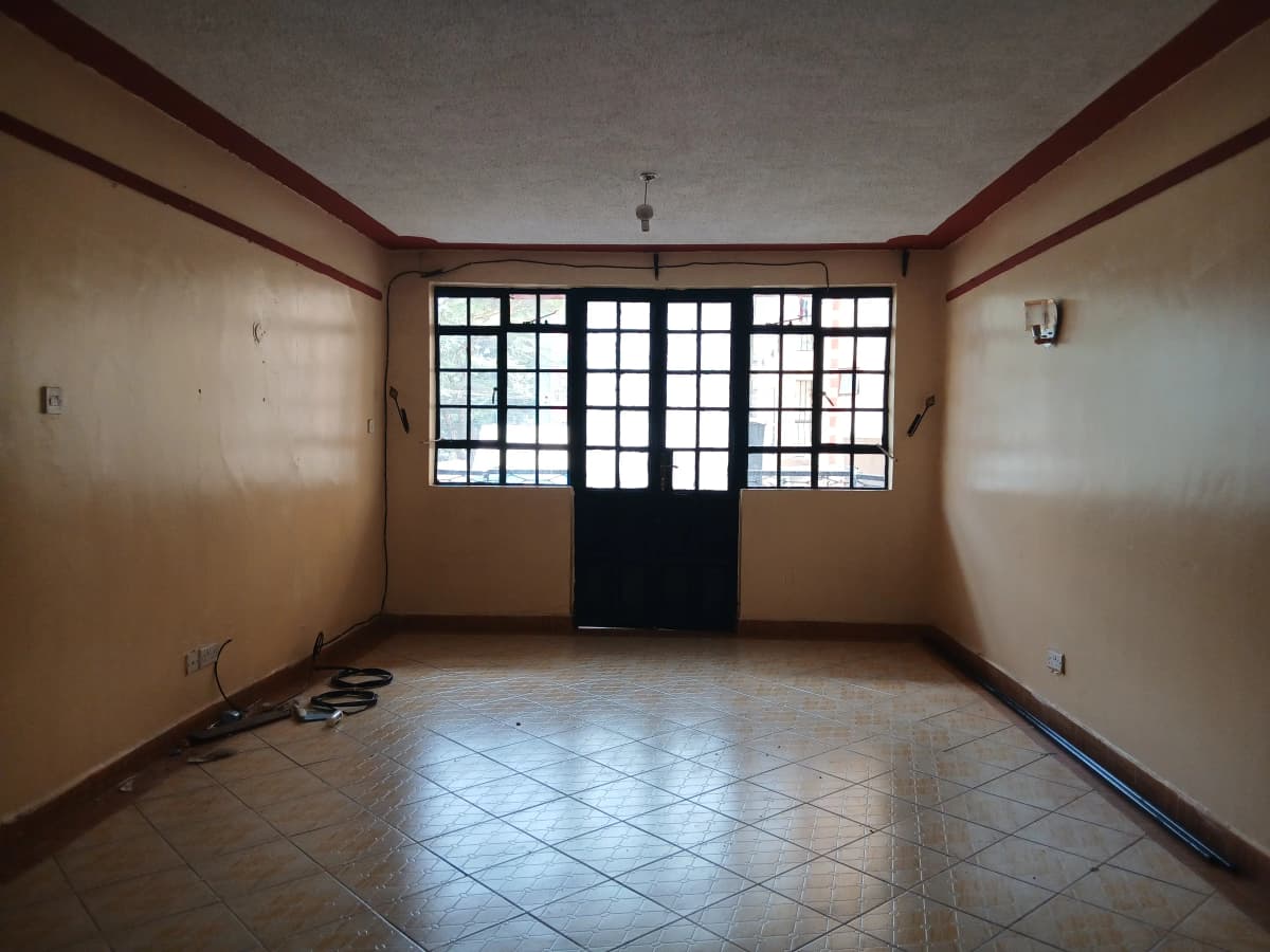 Empty living room with tiled floor and large barred windows