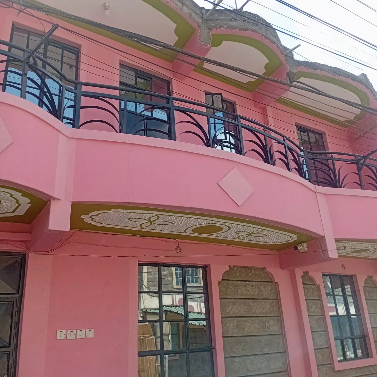 Pink residential building facade with balcony and decorative elements