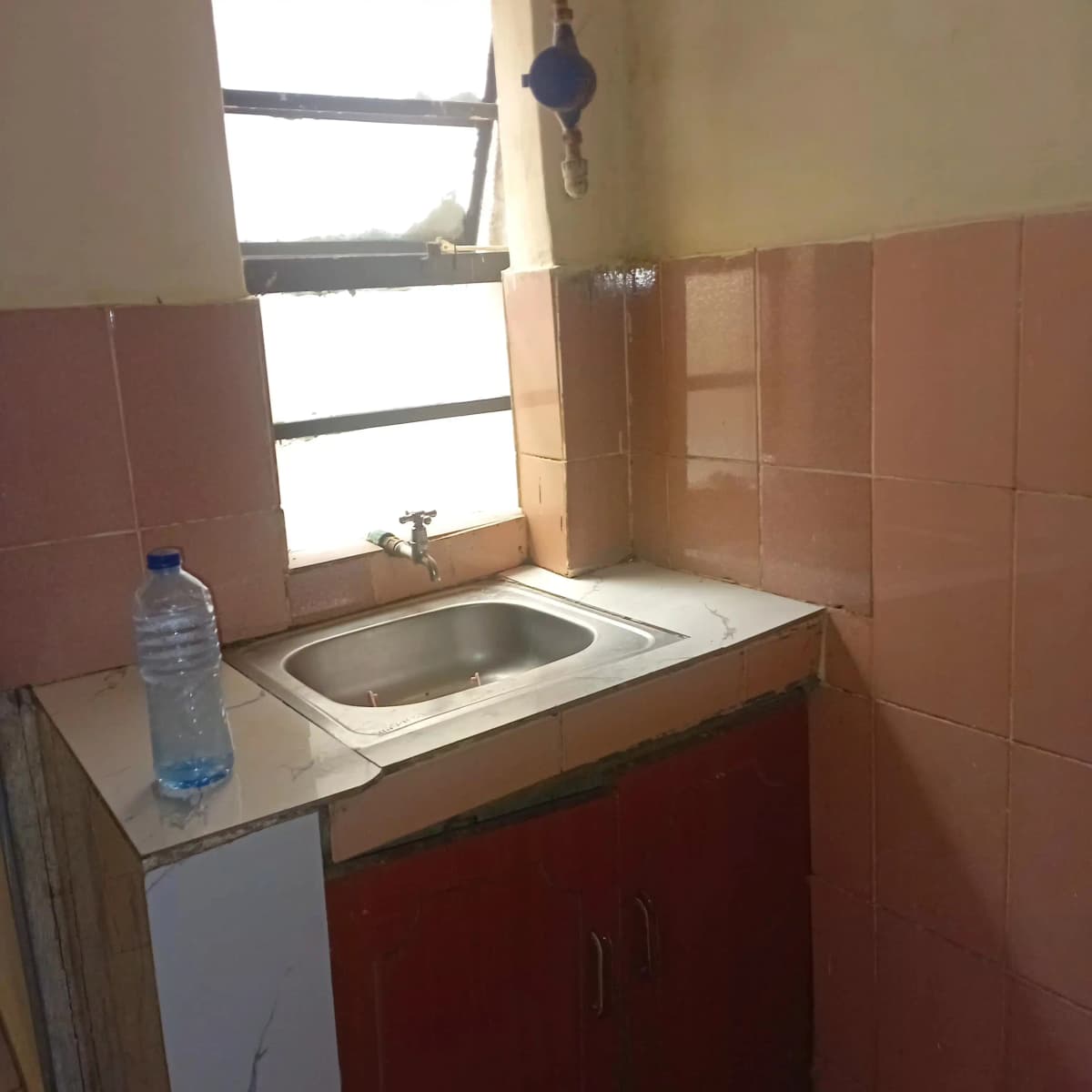 Compact kitchen with red cabinet base and ceramic sink