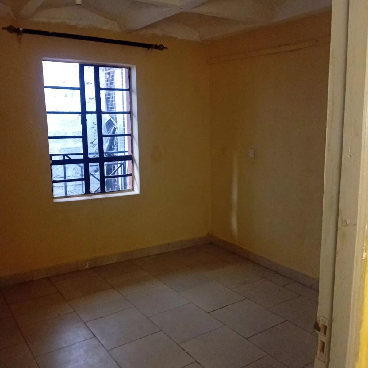 Empty bedroom with yellow walls and tiled flooring