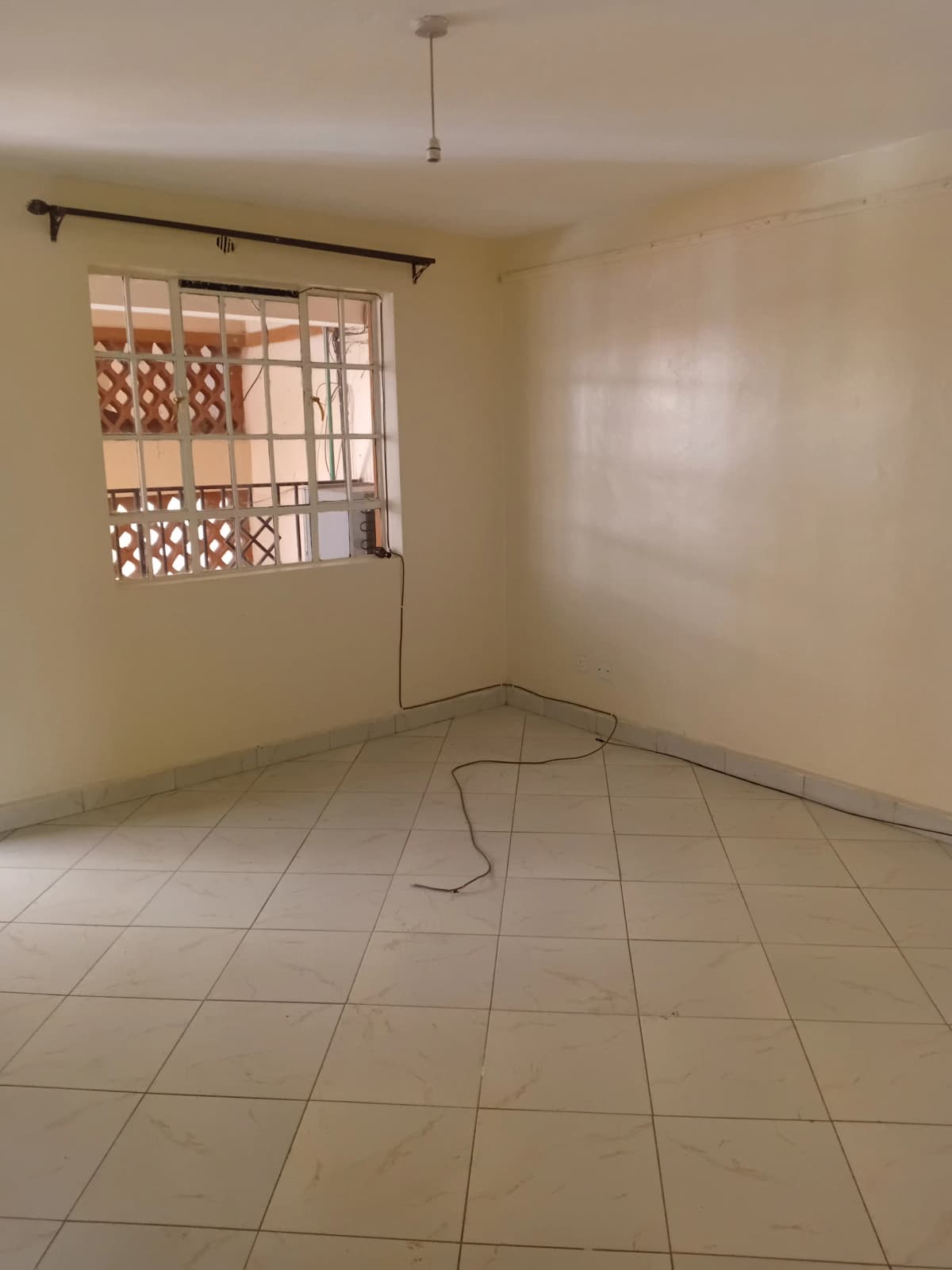 Empty bedroom with tiled floor and barred window
