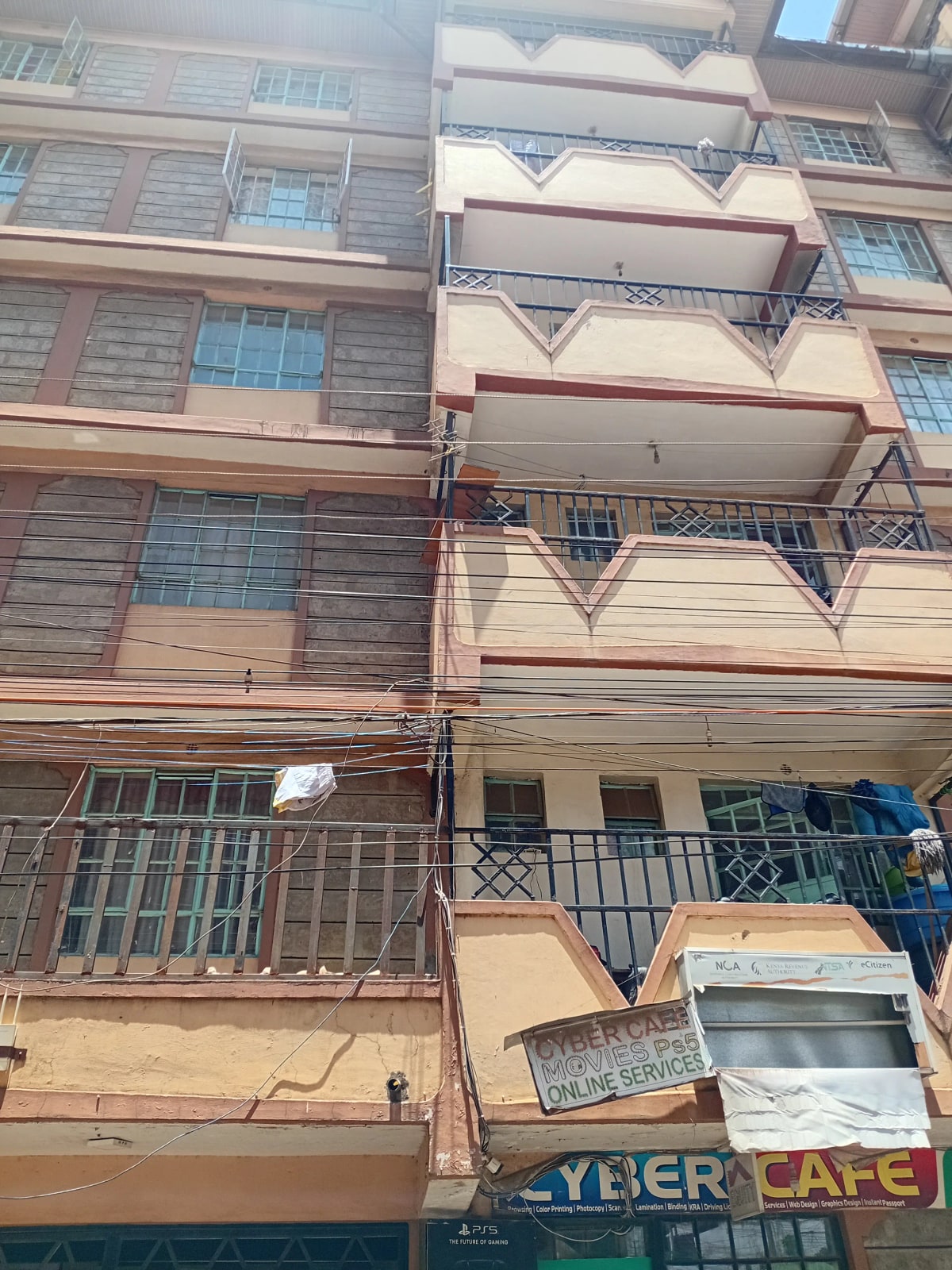 Multi-story residential building facade with balconies and street-level cafe