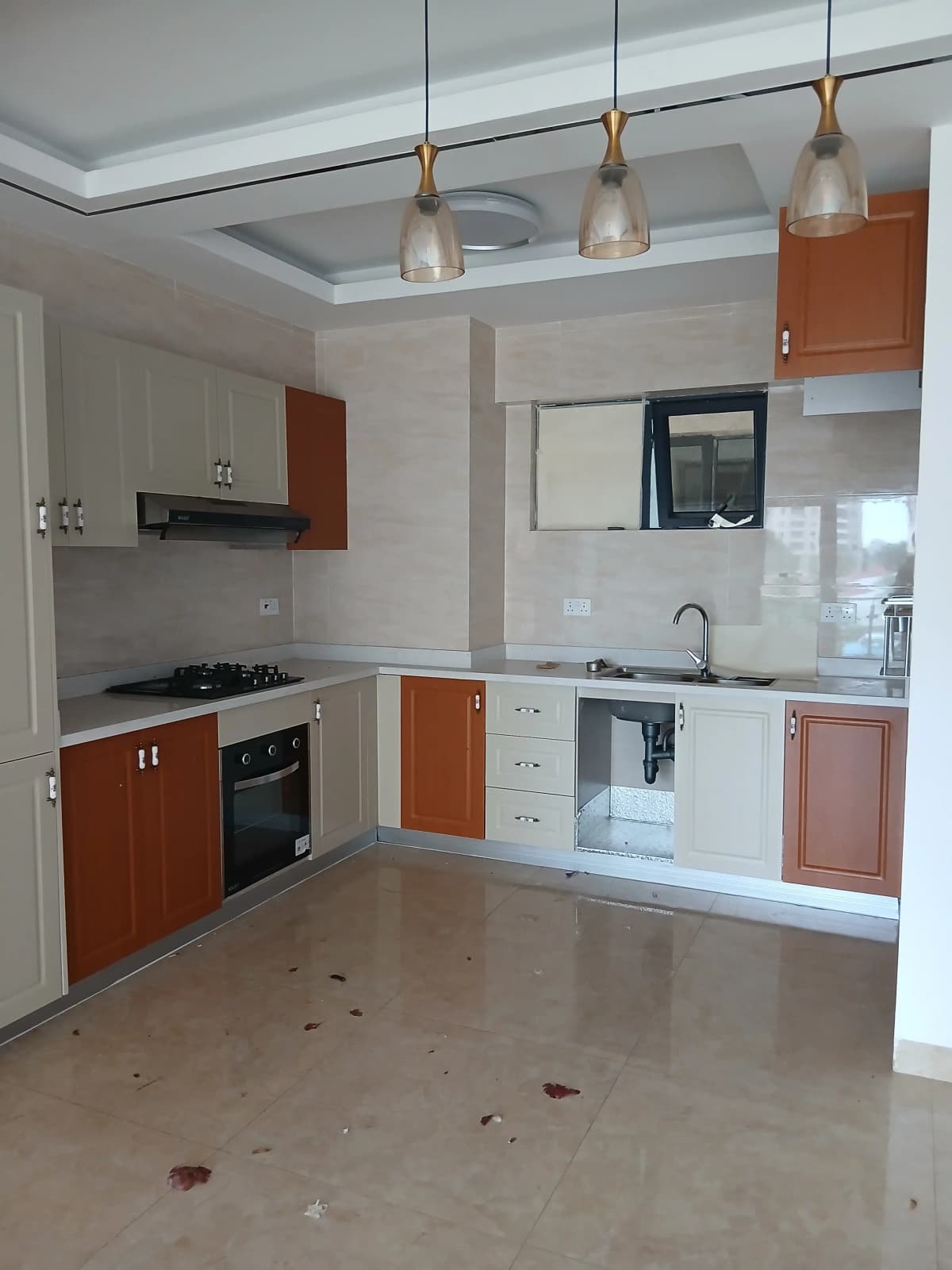 Modern kitchen with orange cabinetry and pendant lighting