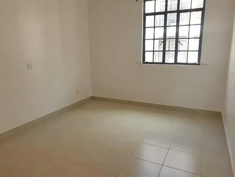 Spacious empty bedroom with tiled flooring and natural light