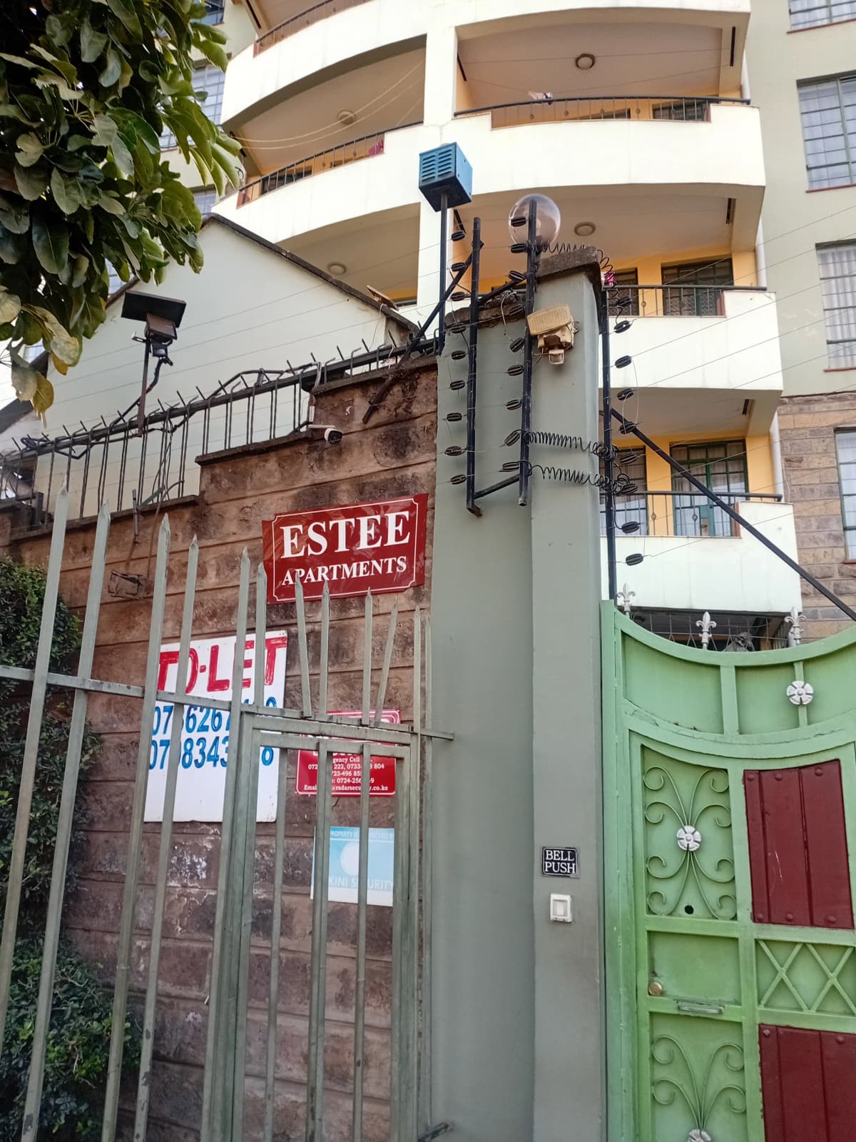 Modern apartment building facade with signage and green gate