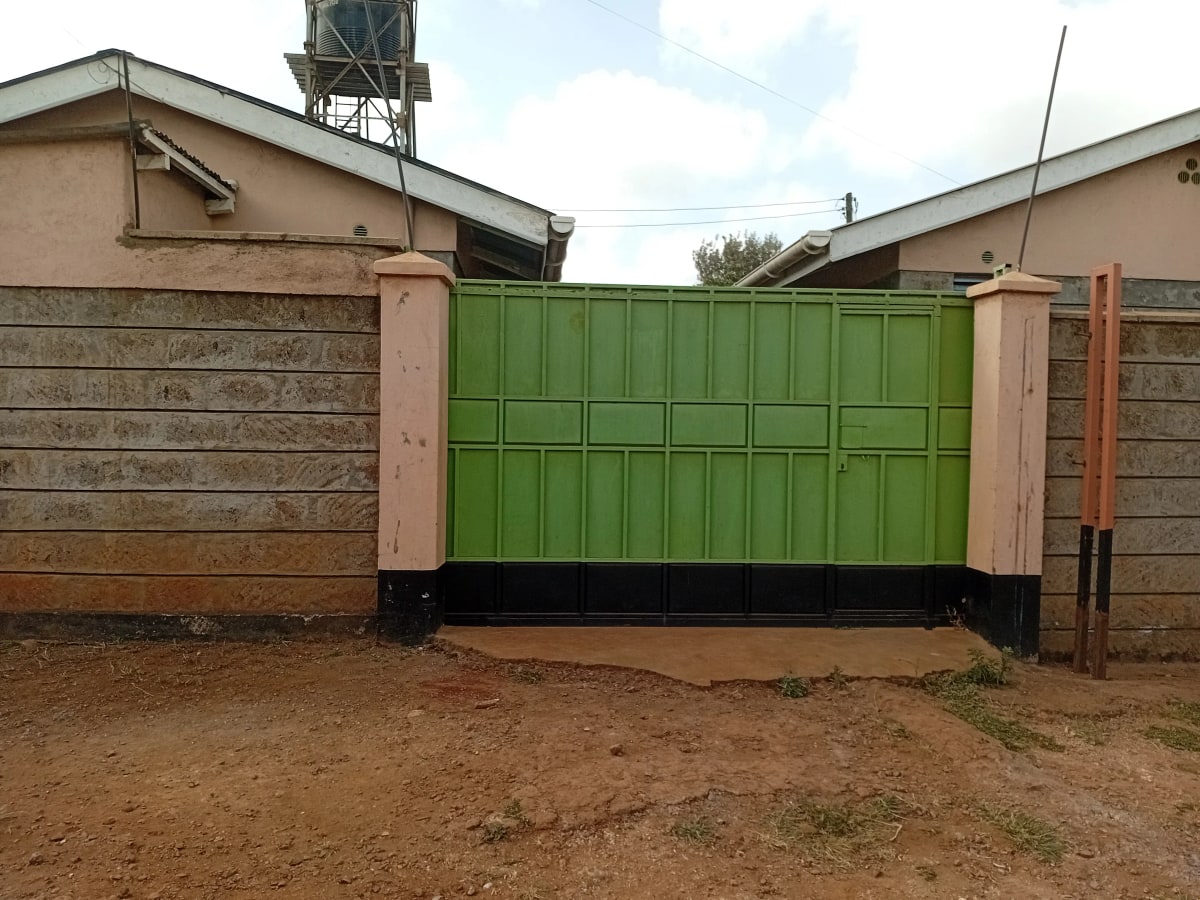 Compound entrance with bright green metal gate and walls
