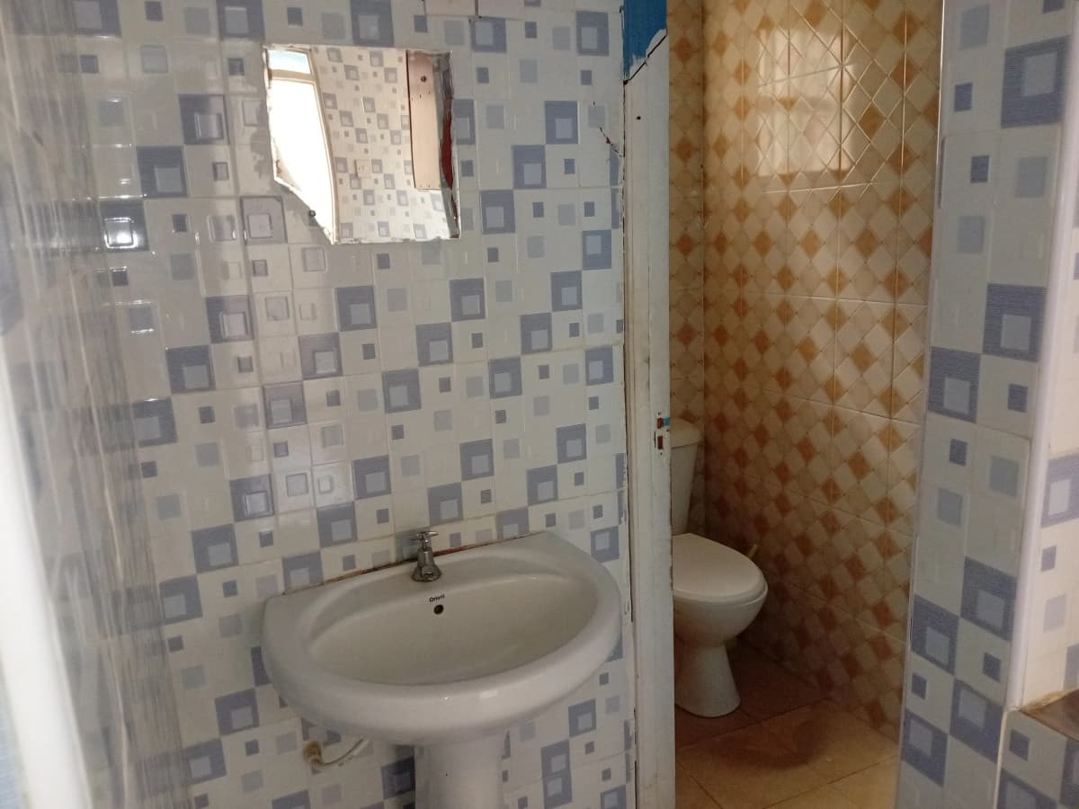 Compact bathroom with pedestal sink and tiled walls