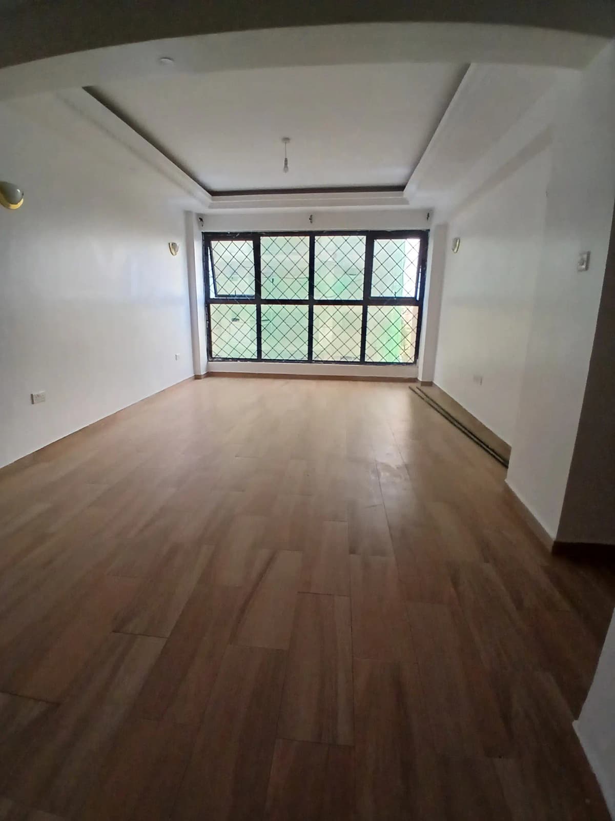 Spacious bedroom with wooden flooring and large windows