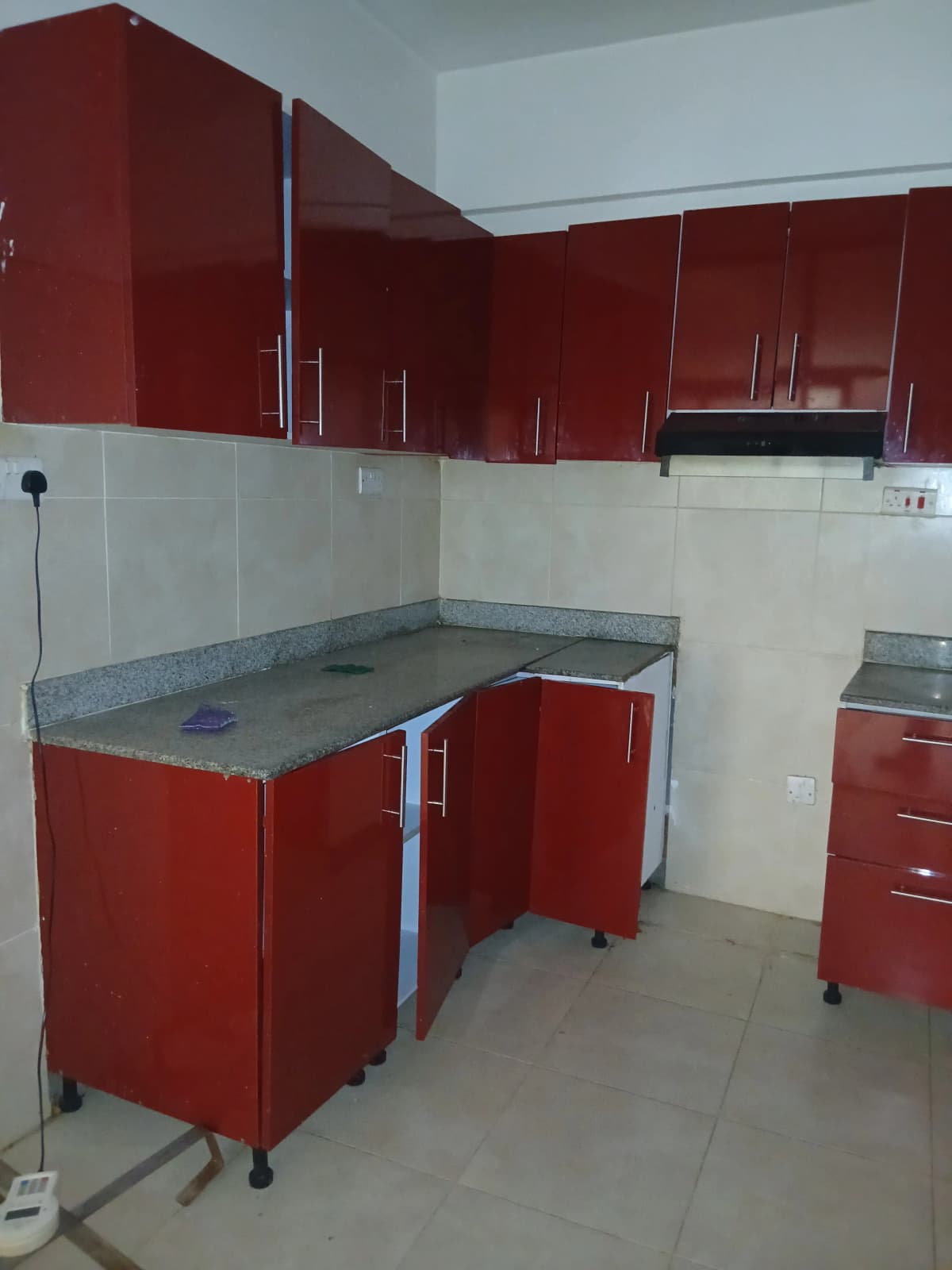 Compact kitchen with red cabinetry and gray countertops