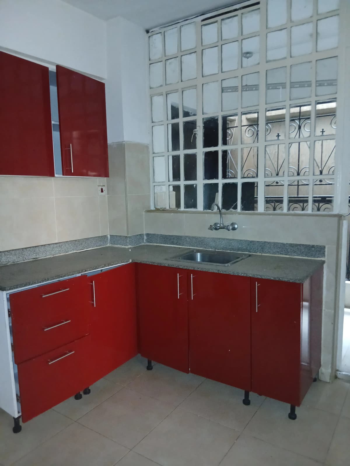 Compact kitchen with red cabinetry and gray countertop