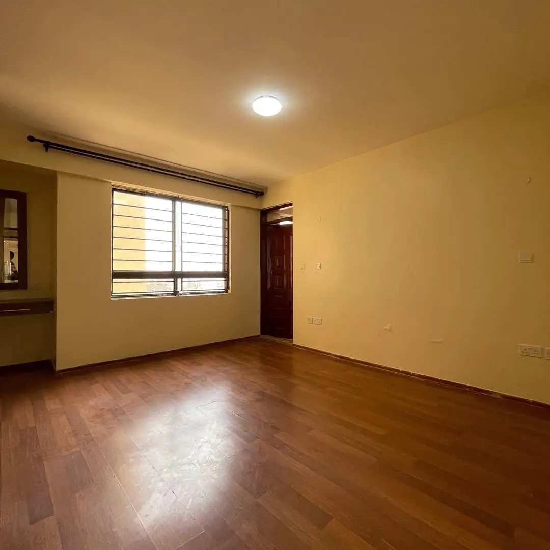 Spacious bedroom with wooden flooring and natural light